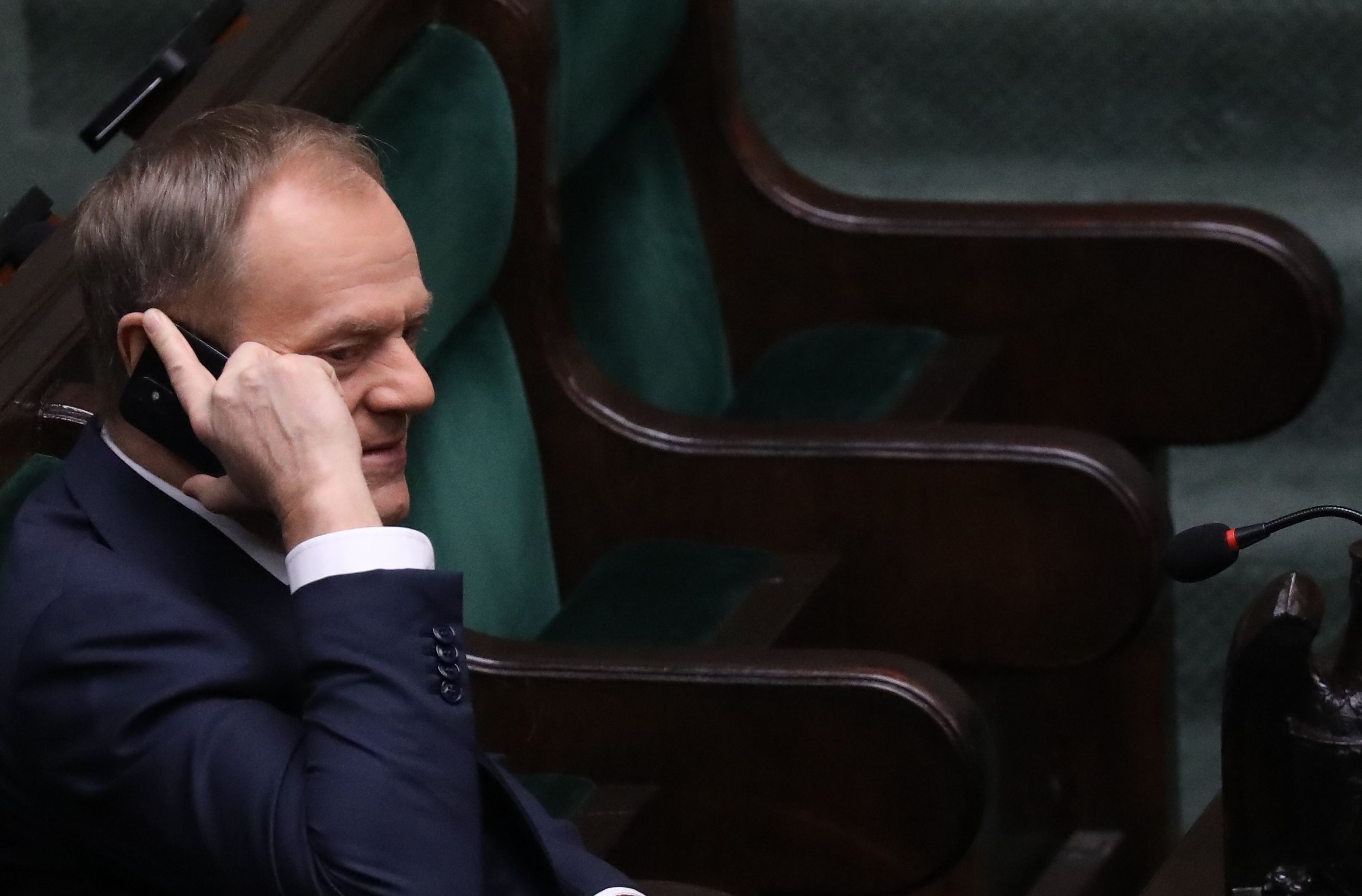 Mężczyzna w ławach rządowych w Sejmie, trzyma telefon komórkowy przy uchu. Donald Tusk, sondaż Ipsos