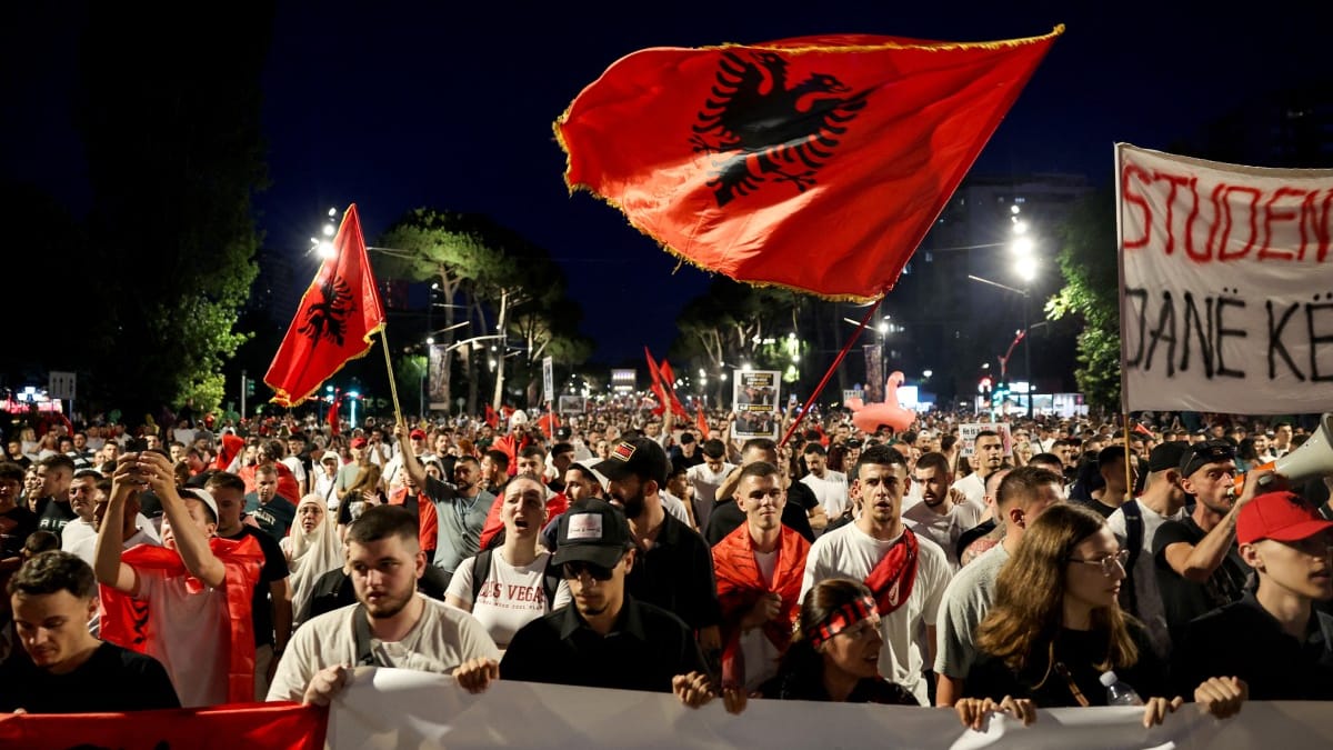 Protestujący trzymają flagi narodowe, gromadząc się przed Kancelarią Premiera Albanii w Tiranie