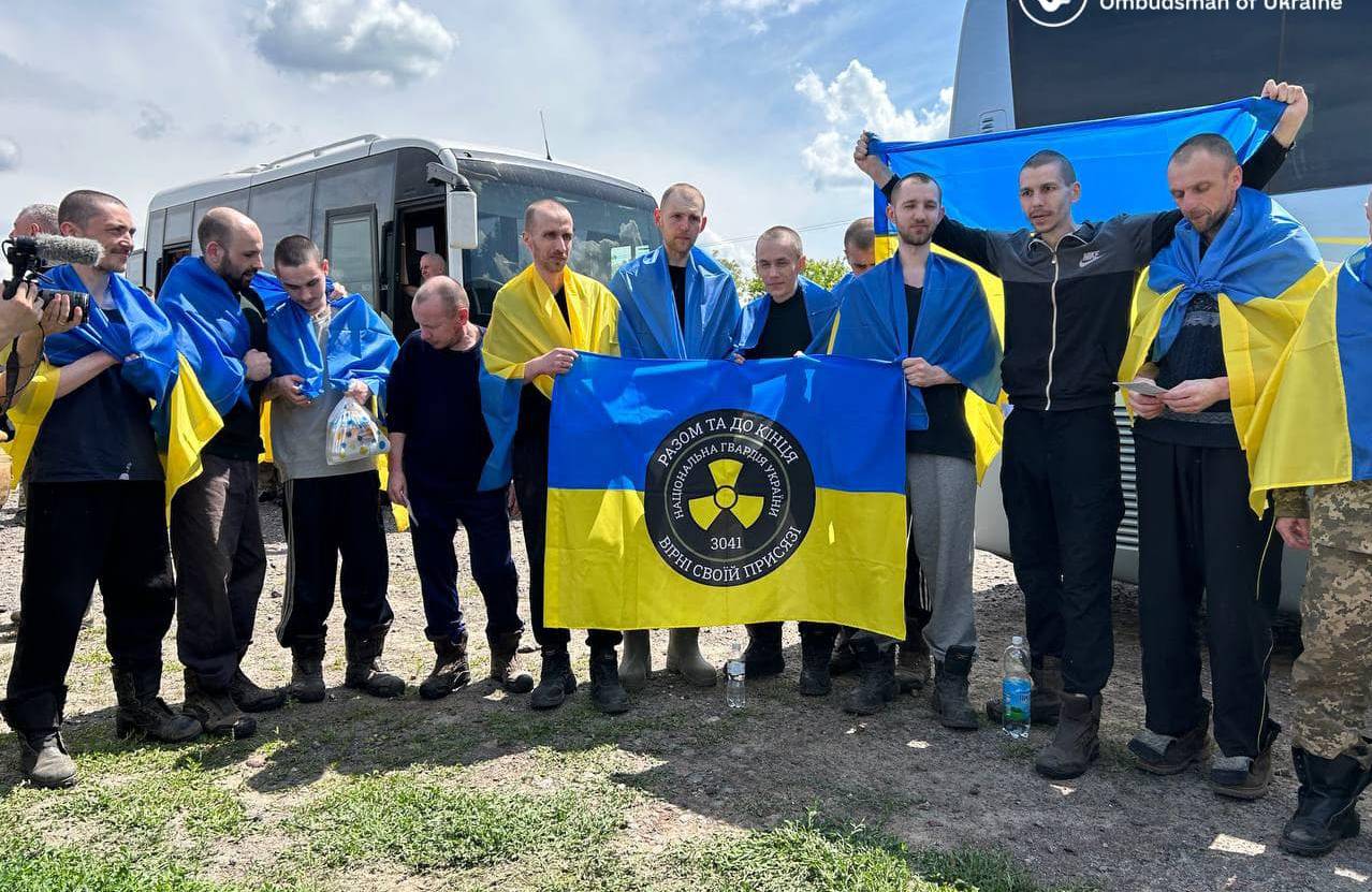 NA zdjęciu są ukraińscy żołnierze, którzy wrócili z niewoli rosyjskiej. Kilku z nich trzyma flagę niebiesko-żółtą