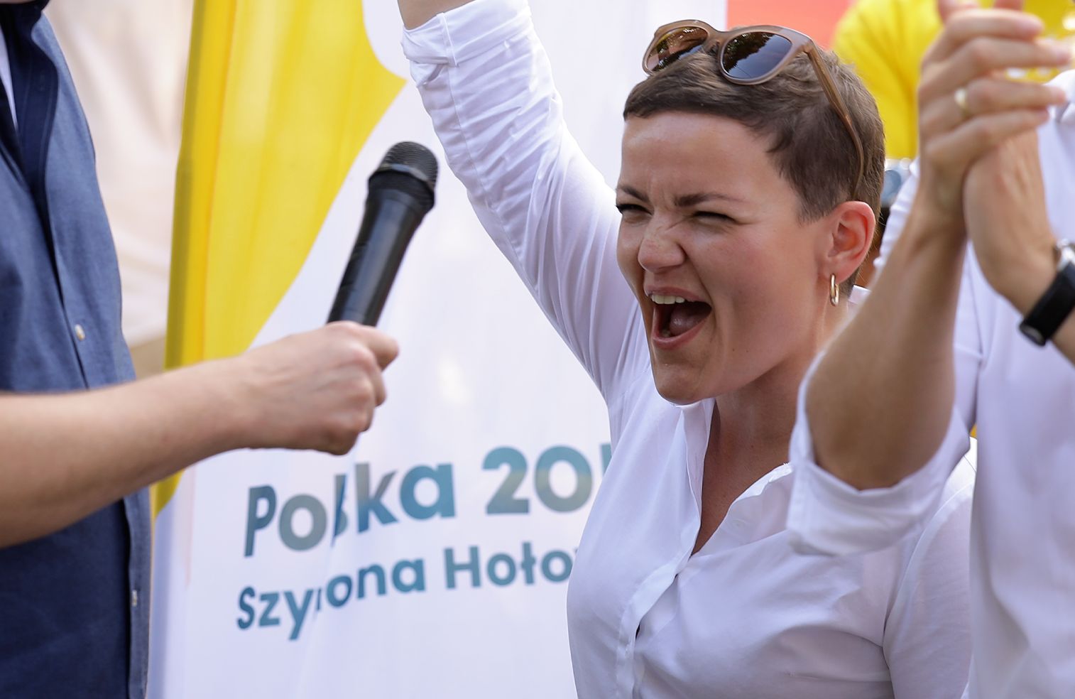 Marta Cienkowska podnosi rękę i radośnie krzyczy, obok stoi Szymon Hołownia z mikrofonem