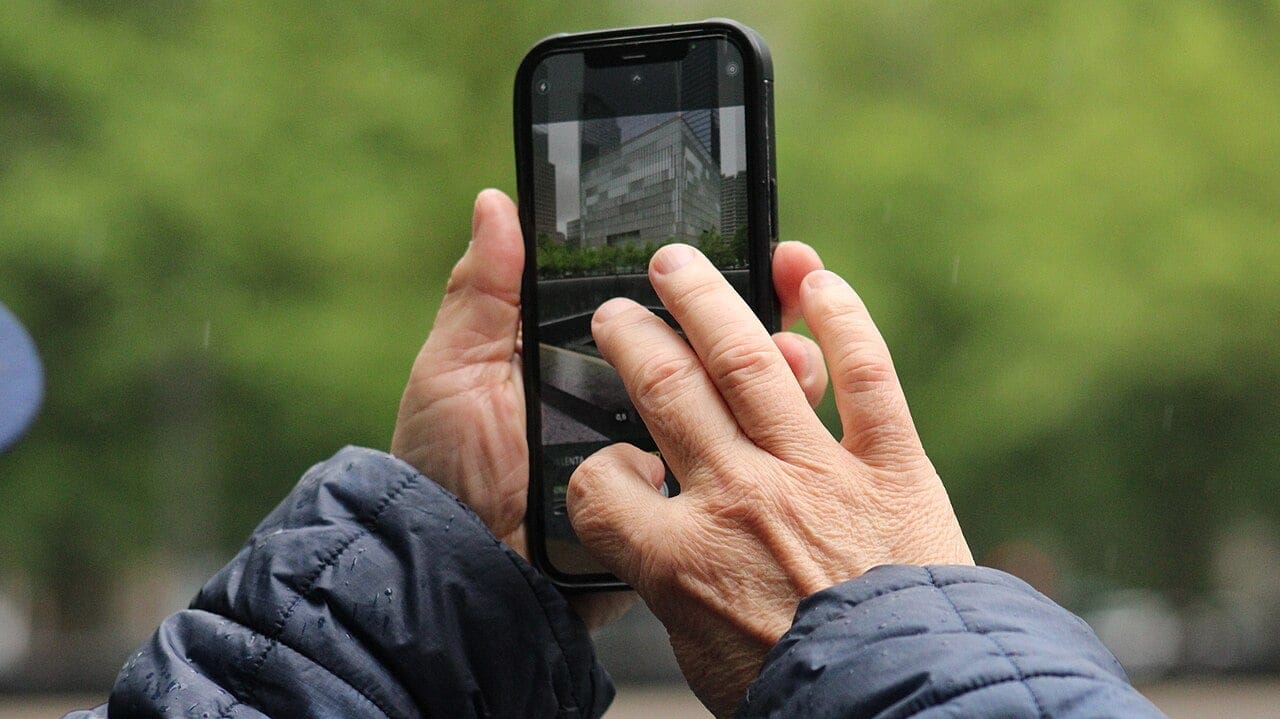 Ręce trzymajace wręku smartfon, widoczny jest ekran, ale obraz na ekranie zamglony