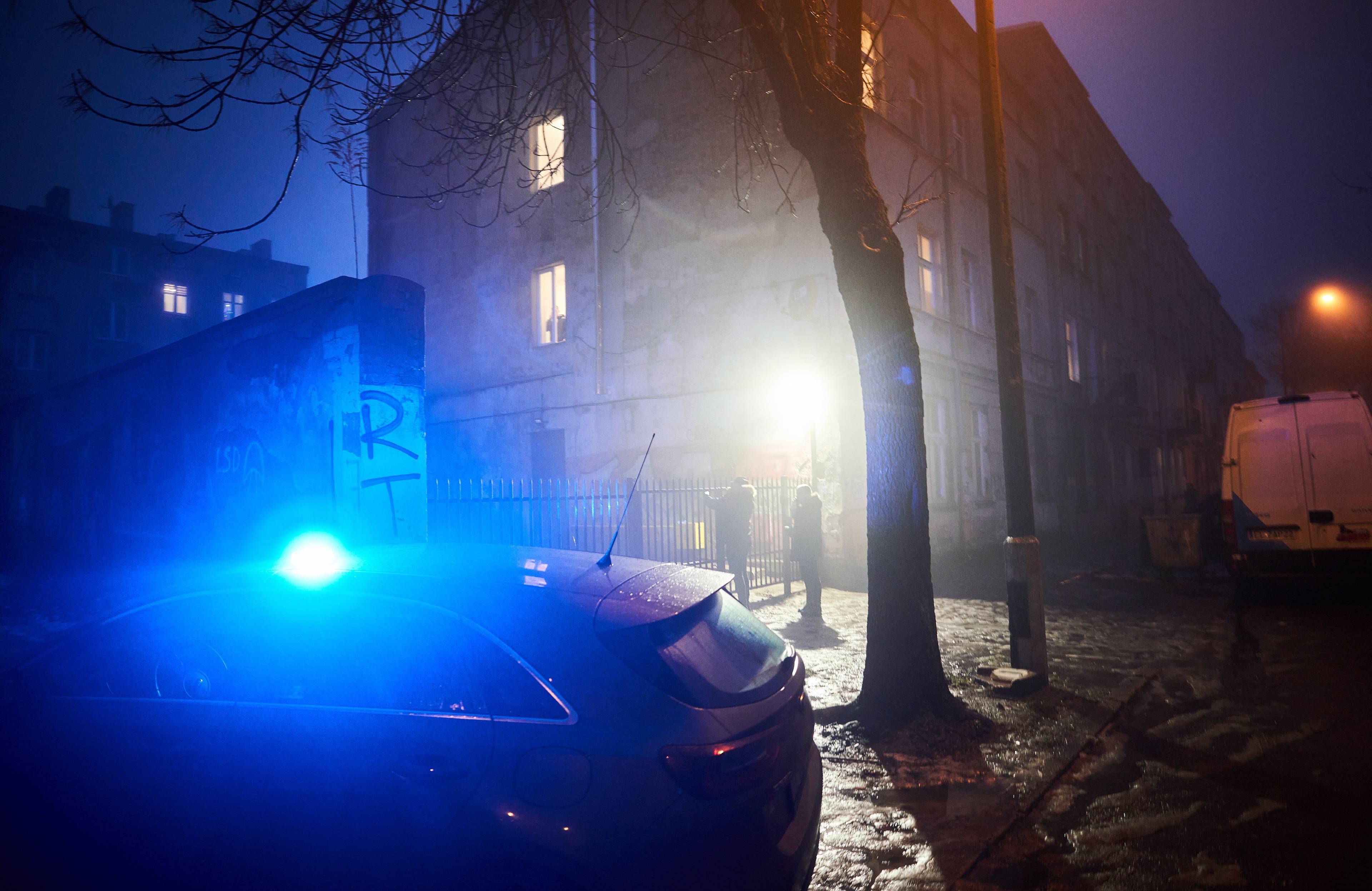 Samochód policyjny z intensywnie niebieskim światłem pod domem o zmierzchu