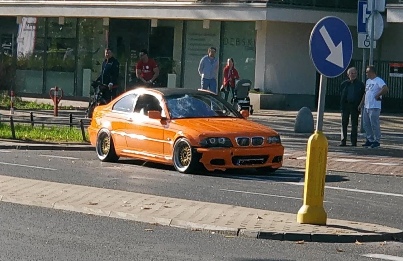 Pomarańczowy samochód marki BMW ze stłuczoną przednią szybą
