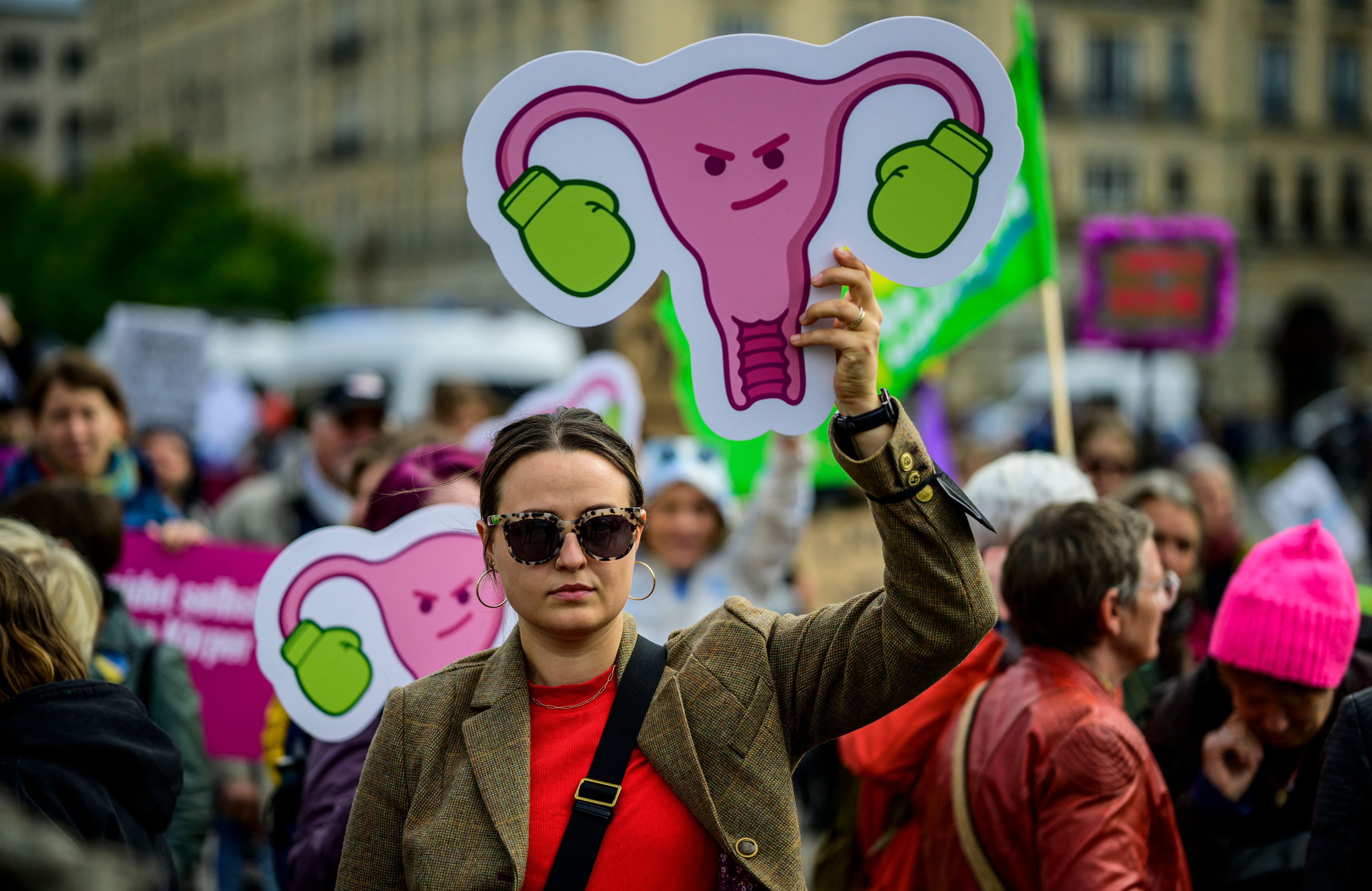 Kobieta z transparentem z macicą i jajnikami - na jajniki naciągnięte rękawice bokserskie
