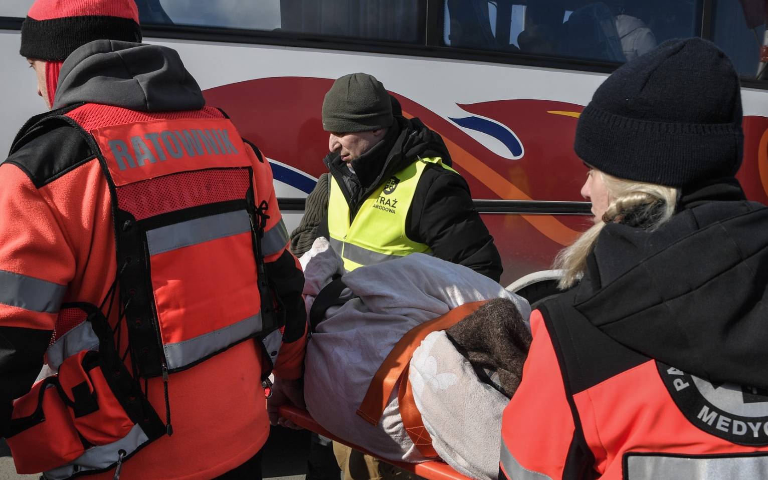 Medics carry a person after crossing the Ukrainian-Polish border at the Medyka border crossing, southeastern Poland, on March 10, 2022. - The UN says at least 2.2 million people have fled Ukraine, with more than half now in Poland. It has called the exodus Europe's fastest-growing refugee crisis since World War II. (Photo by Louisa GOULIAMAKI / AFP)