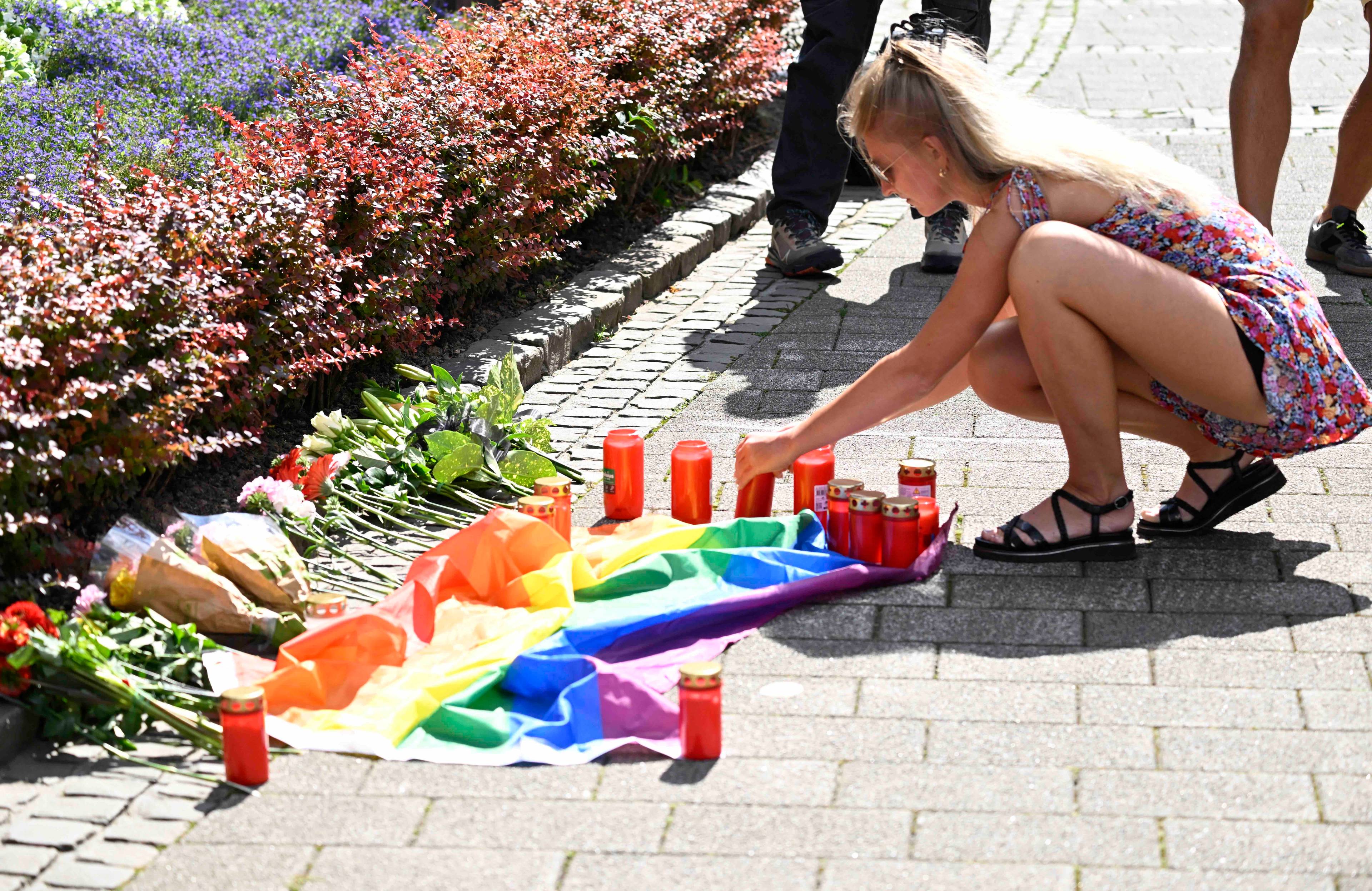 Dziewczyna stawia znicze wokół tęczowej flagi, rozłożonej na chodniku. Atak w Solingen