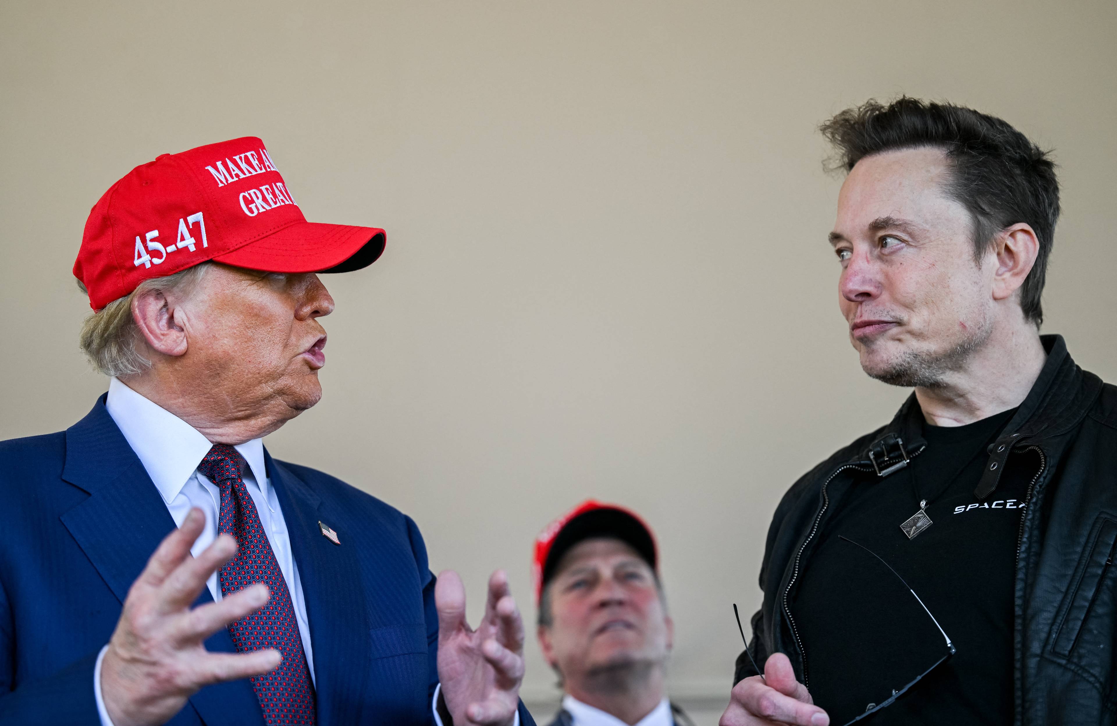 Męczyzna w czerwonej czapce i meżczyzna w blizie: Trump i Musk