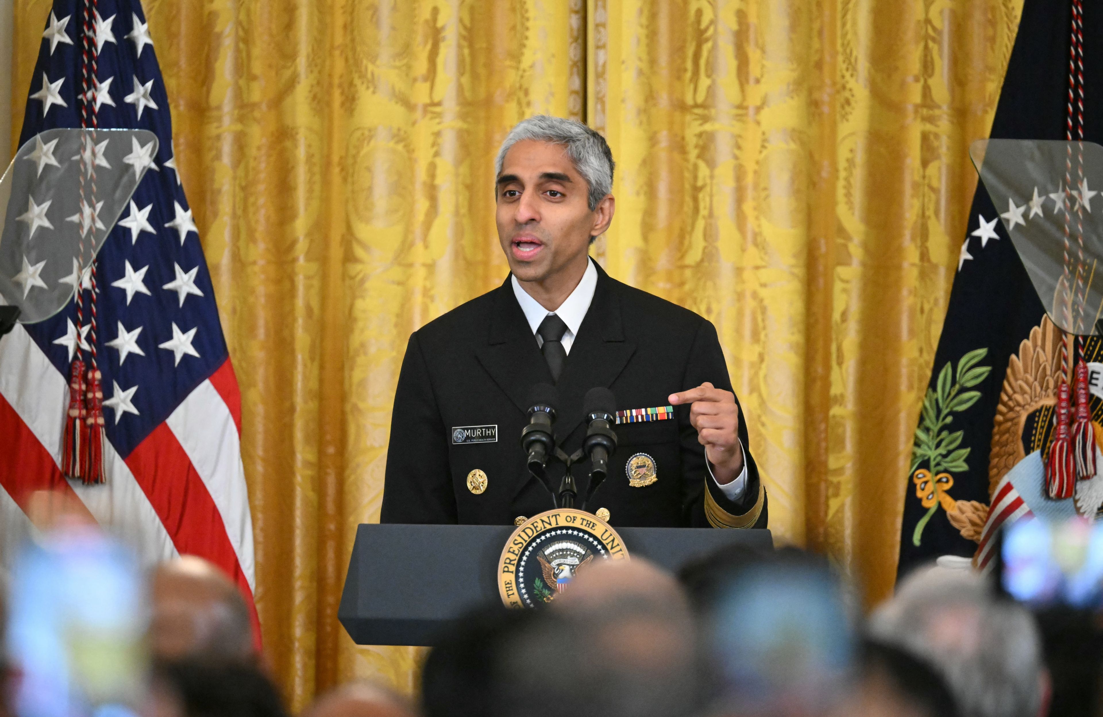 Chirurg generalny USA Vivek Murthy przemawia za panelem na złotym tle