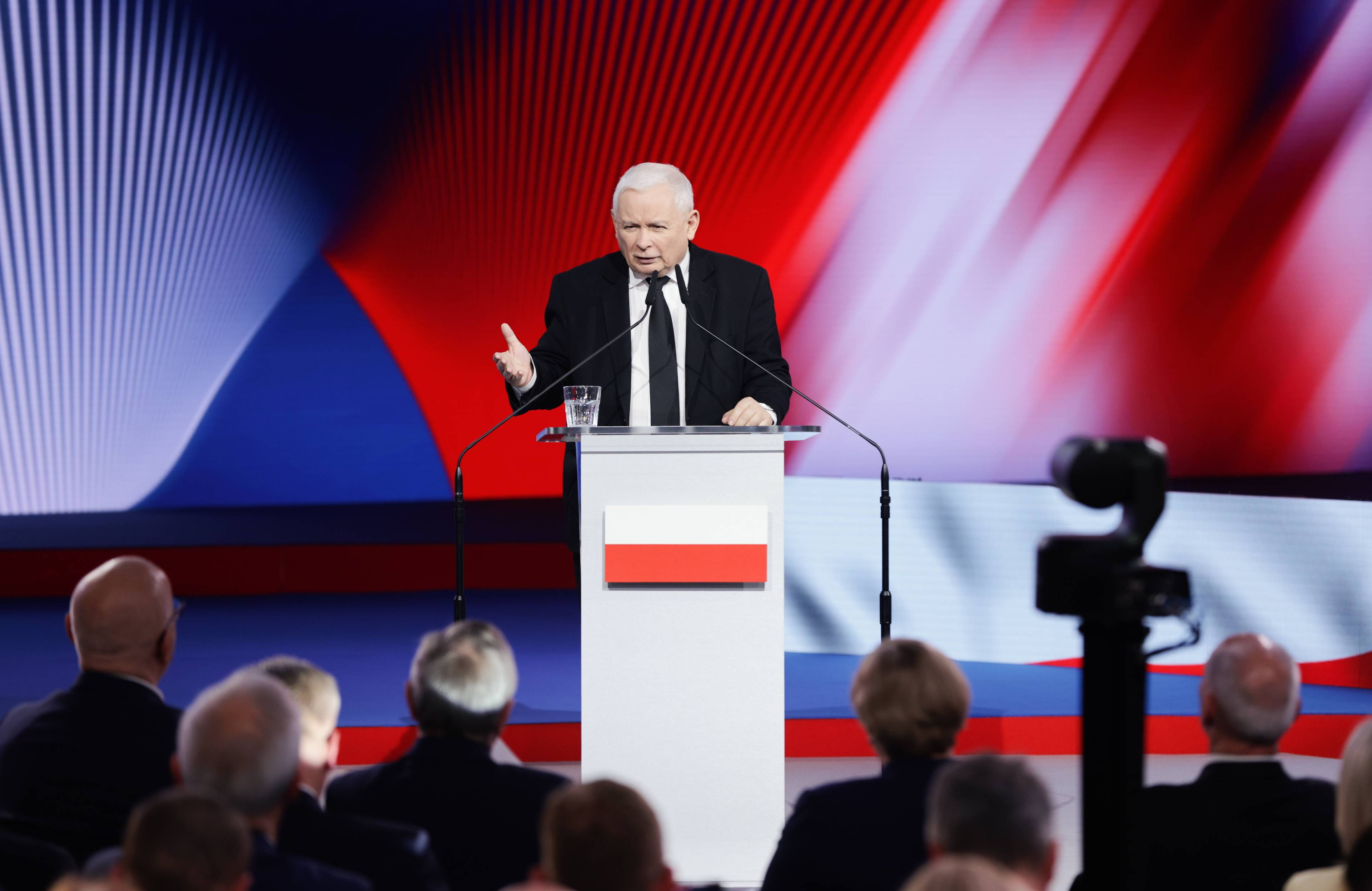 Kaczyński przy mównicy, na której widać biało czerwoną flagę