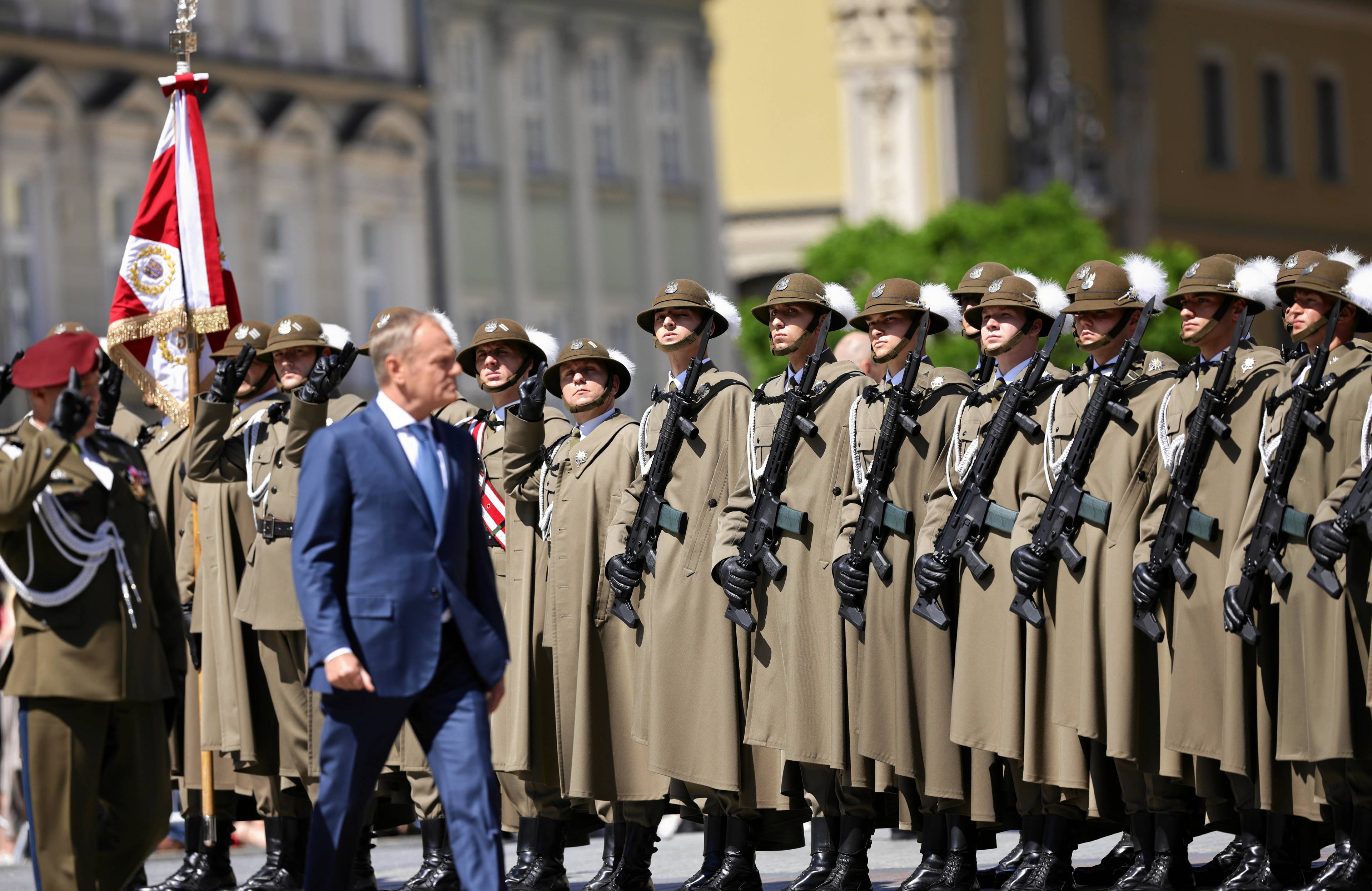 Premier Donald Tusk maszeruje na tle żołnierzy ustawionych w szeregu na krakowskim rynku