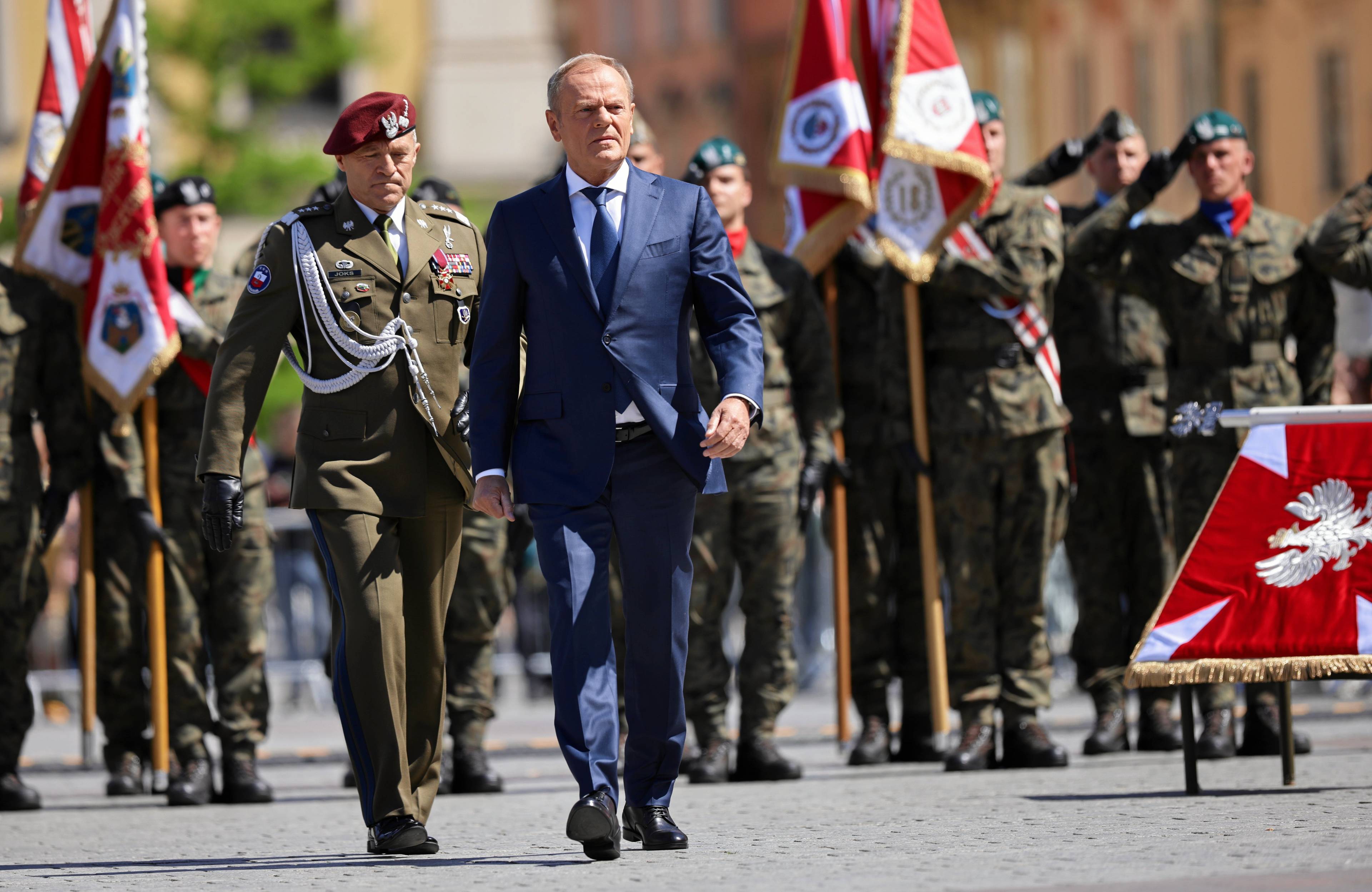 premier Tusk w garniturze maszeruje przed żołnierzami w galowych mundurach