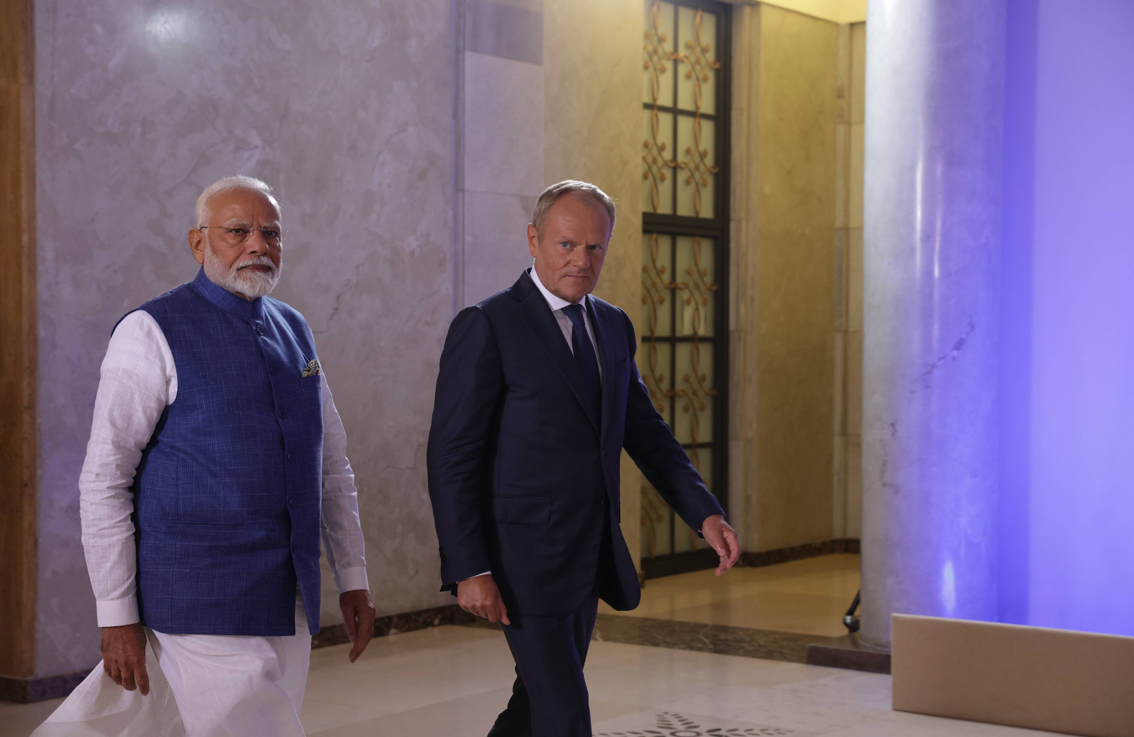 premierzy Donald Tusk i Narendra Modi idą przez korytarz