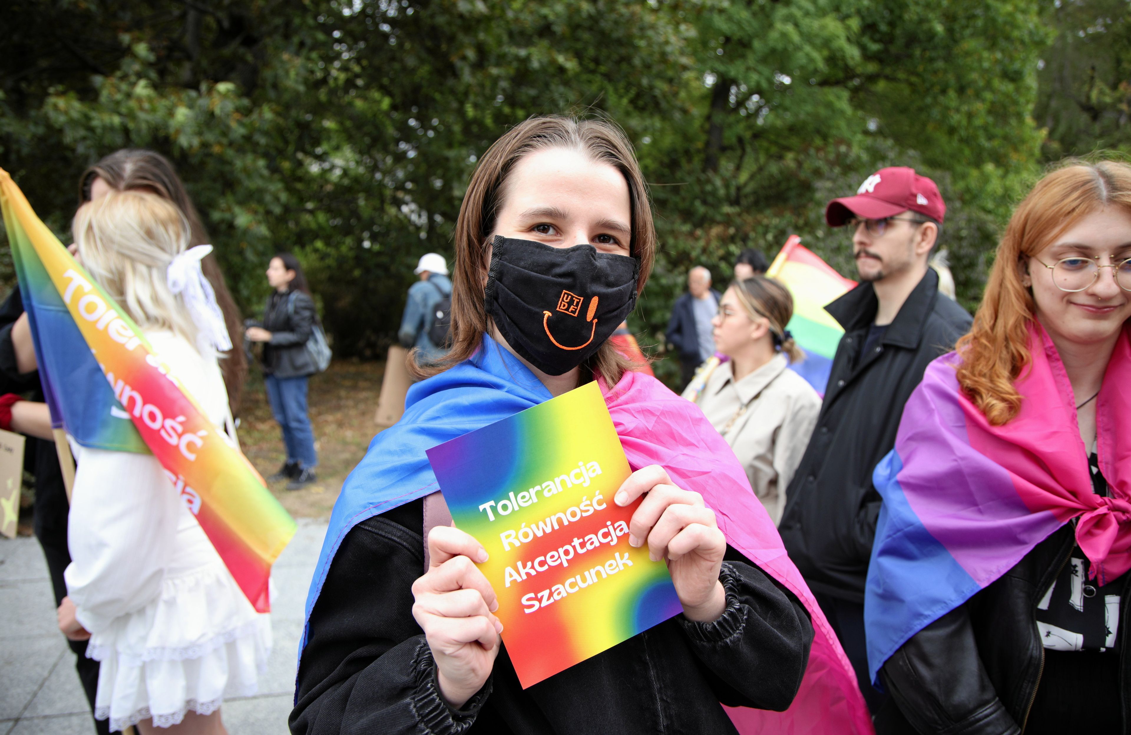 osoba trzyma tęczową ulotkę z napisem "tolerancja, akceptacja, szacunek"