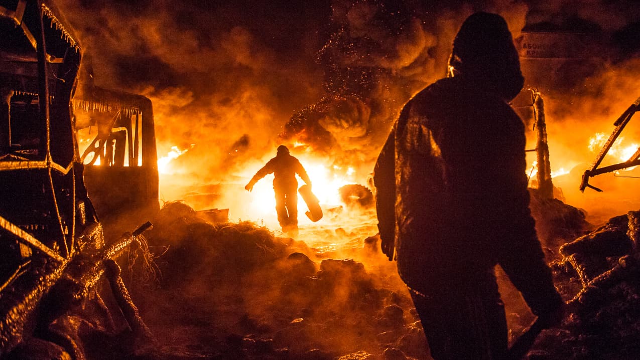 UKRAINE, Kiev : Ukrainian anti-government protesters walk past burning tyres during clashes with riot police in central Kiev early on January 25, 2014. Protesters and Ukrainian police were locked in a tense standoff in Kiev after a night of sporadic clashes that erupted despite a truce and offer of concessions by President Viktor Yanukovych. AFP PHOTO / VOLODYMYR SHUVAYEV