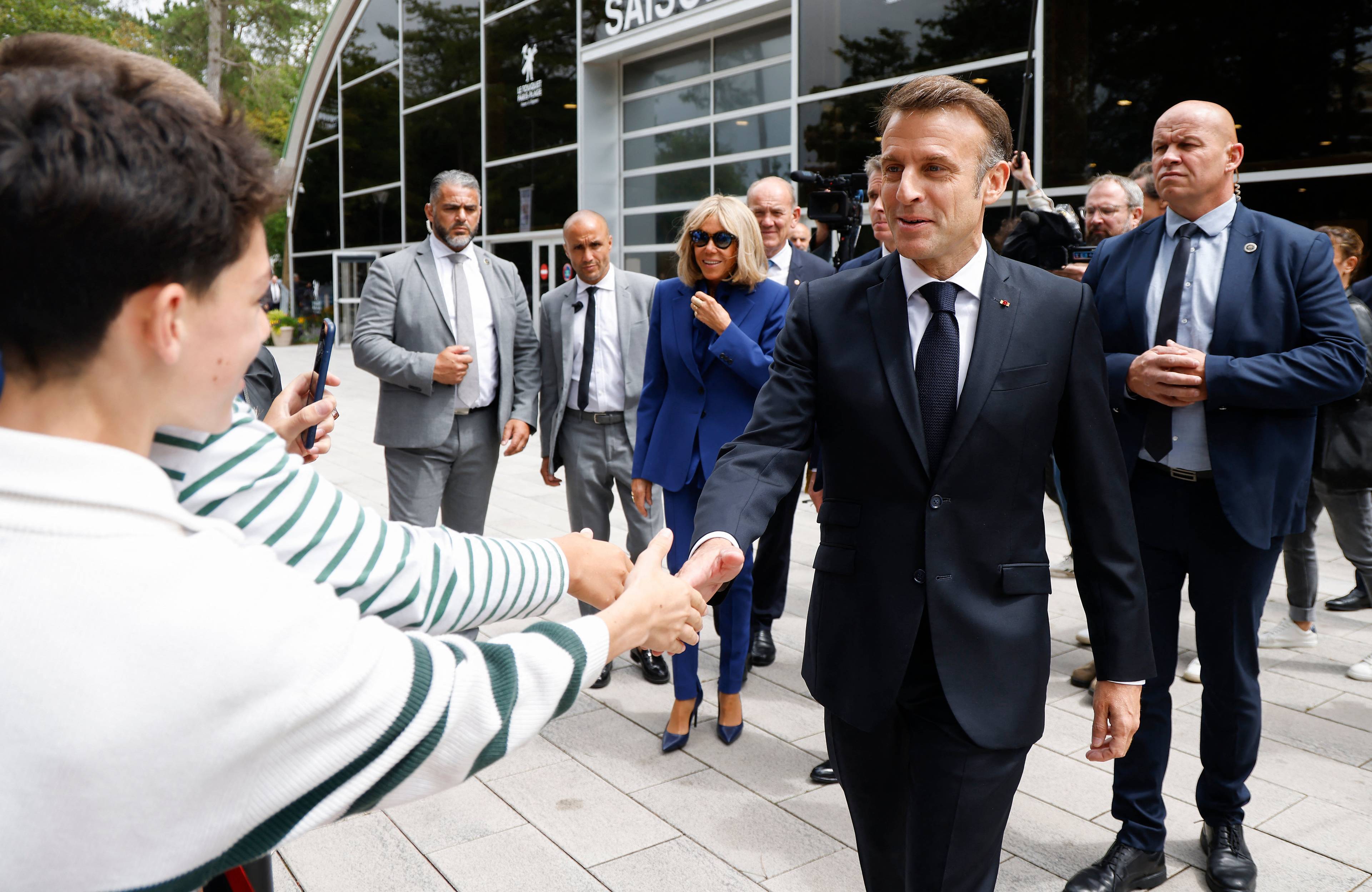Emmanuel Macron ściska dłoń ludziom po głosowaniu