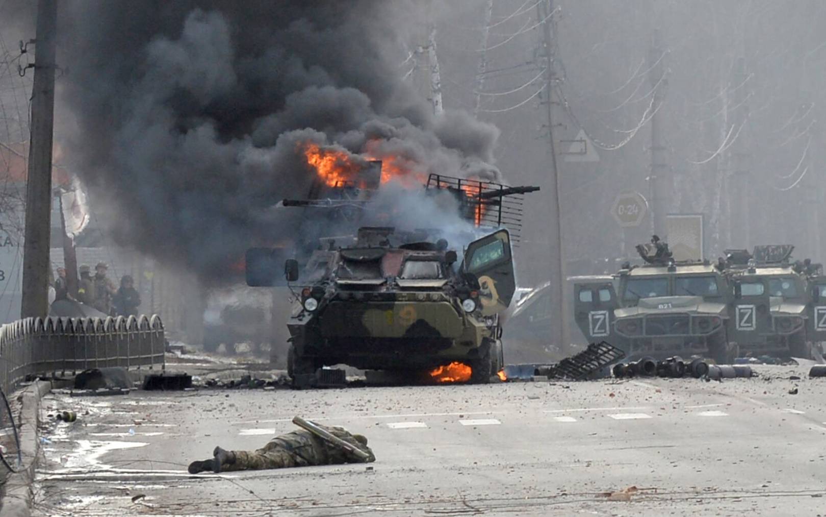 This photograph taken on February 27, 2022 shows a Russian Armoured personnel carrier (APC) burning next to unidentified soldier's body during fight with the Ukrainian armed forces in Kharkiv. - Ukrainian forces secured full control of Kharkiv on February 27, 2022 following street fighting with Russian troops in the country's second biggest city, the local governor said. (Photo by Sergey BOBOK / AFP) / “The mention [next to unidentified soldier's body] has been added to the caption and the erroneous mention[s] appearing in the metadata of this photo by Sergey BOBOK has been modified in AFP systems in the following manner: [February 27] instead of [February 26]. Please immediately remove the erroneous mention[s] from all your online services and delete it (them) from your servers. If you have been authorized by AFP to distribute it (them) to third parties, please ensure that the same actions are carried out by them. Failure to promptly comply with these instructions will entail liability on your part for any continued or post notification usage. Therefore we thank you very much for all your attention and prompt action. We are sorry for the inconvenience this notification may cause and remain at your disposal for any further information you may require.”