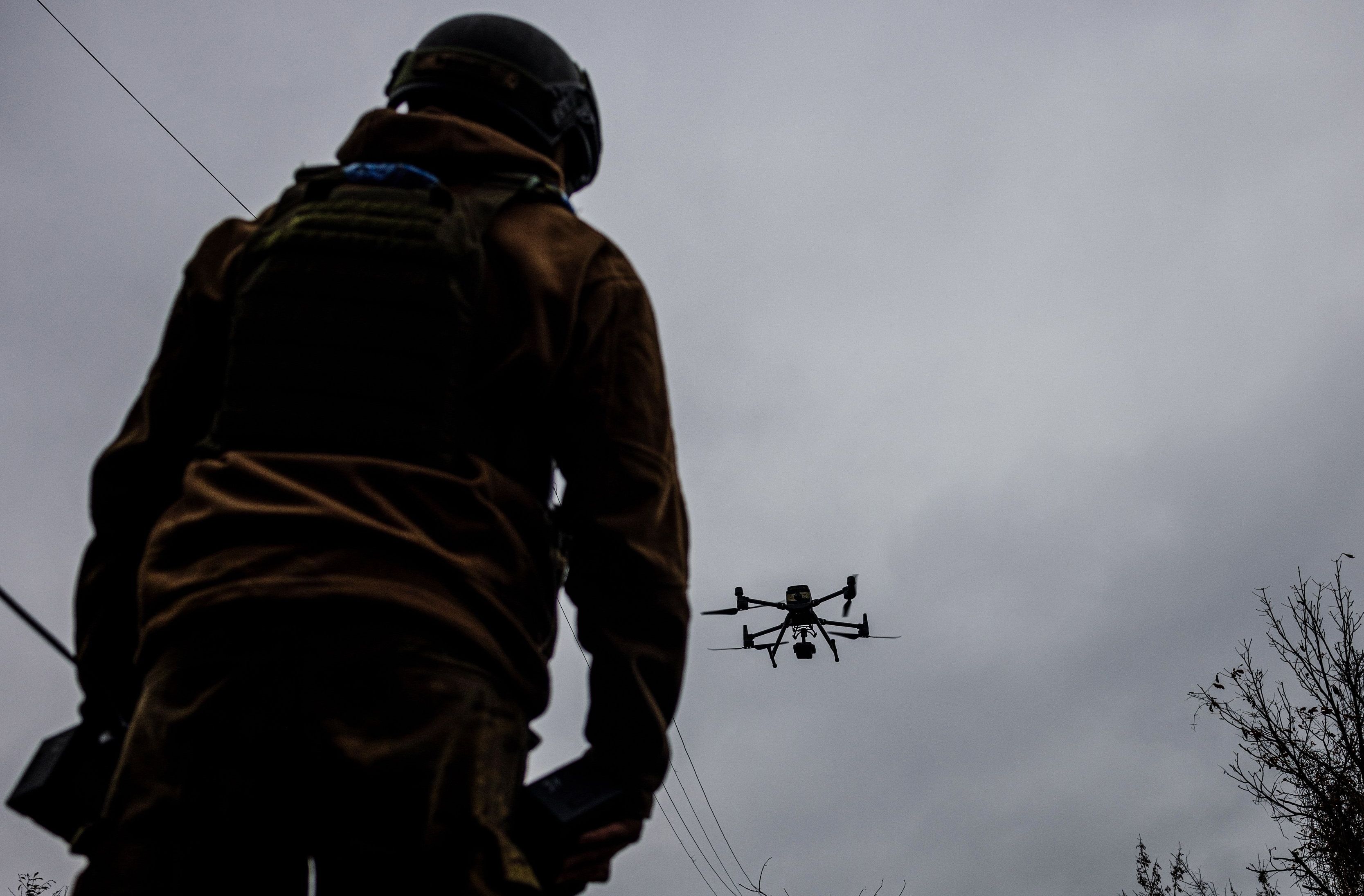 Żołnierz widziany z tyłu, przed nim unosio się w powietrzu mały dron