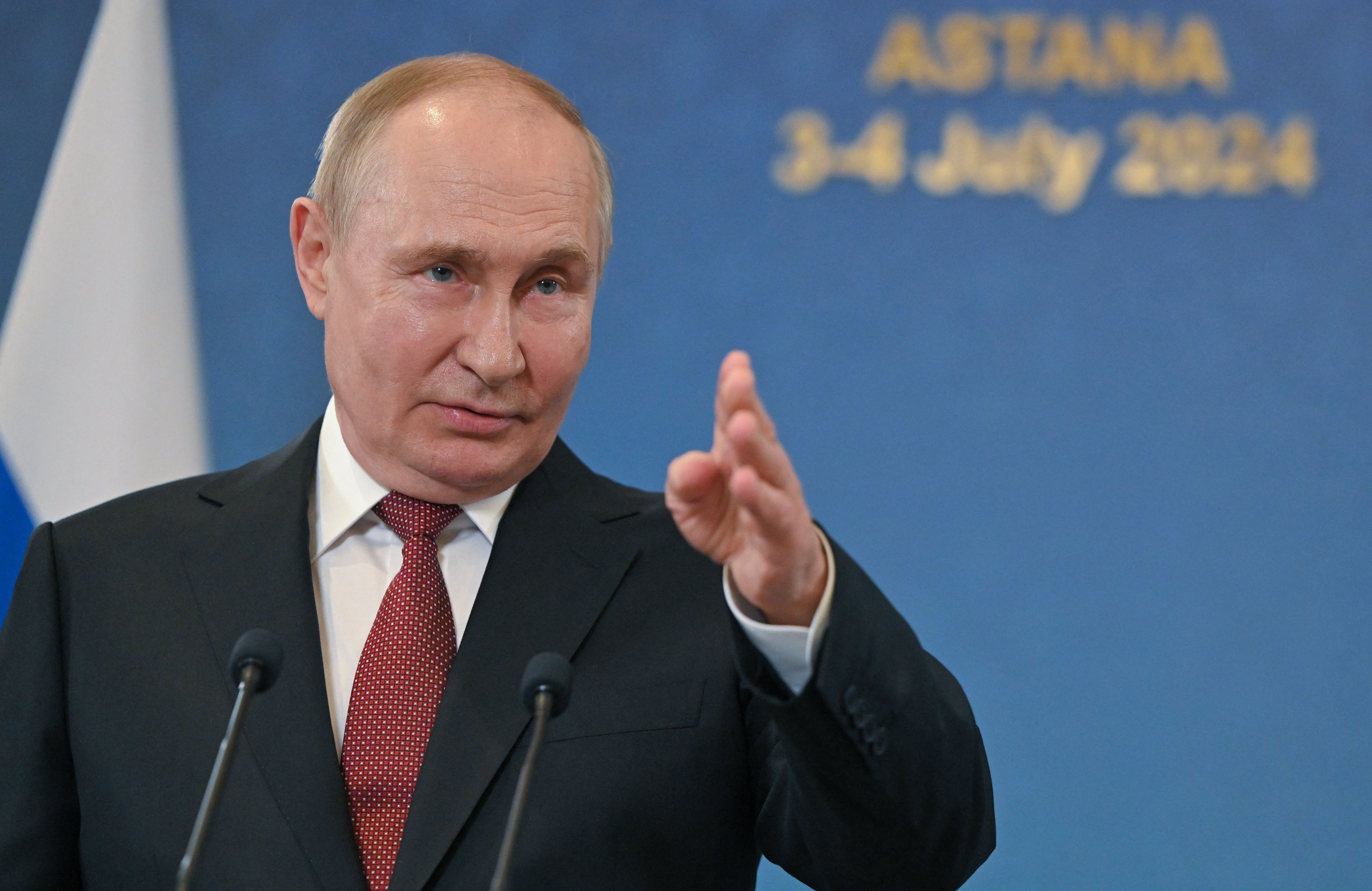 Mężczyzna - Putin - stoi z wyciągniętą ręką