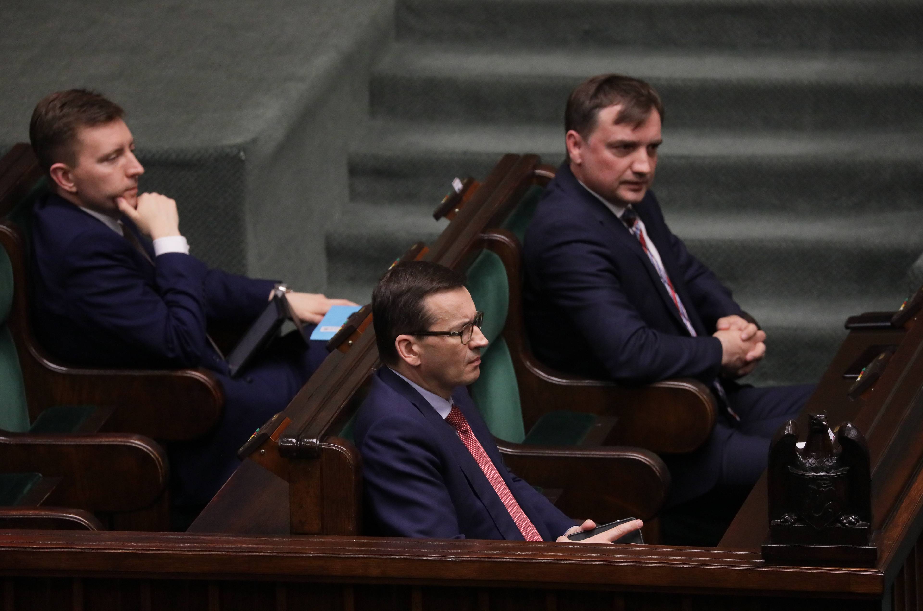 Zbigniew Ziobro i Mateusz Morawiecki na posiedzeniu Sejmu: siedzą obok siebie w ławach rządowych, patrzą na salę plenarną