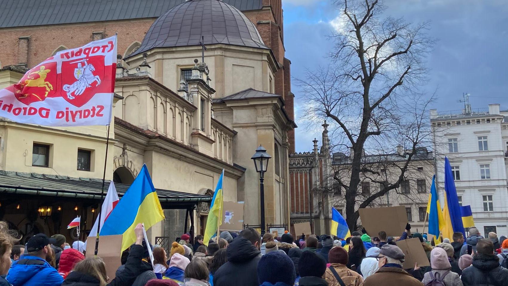 Ludzie idą ulica Stolarską w Krakowie. Niosą żółto-błekitne, ukraińskie flagi