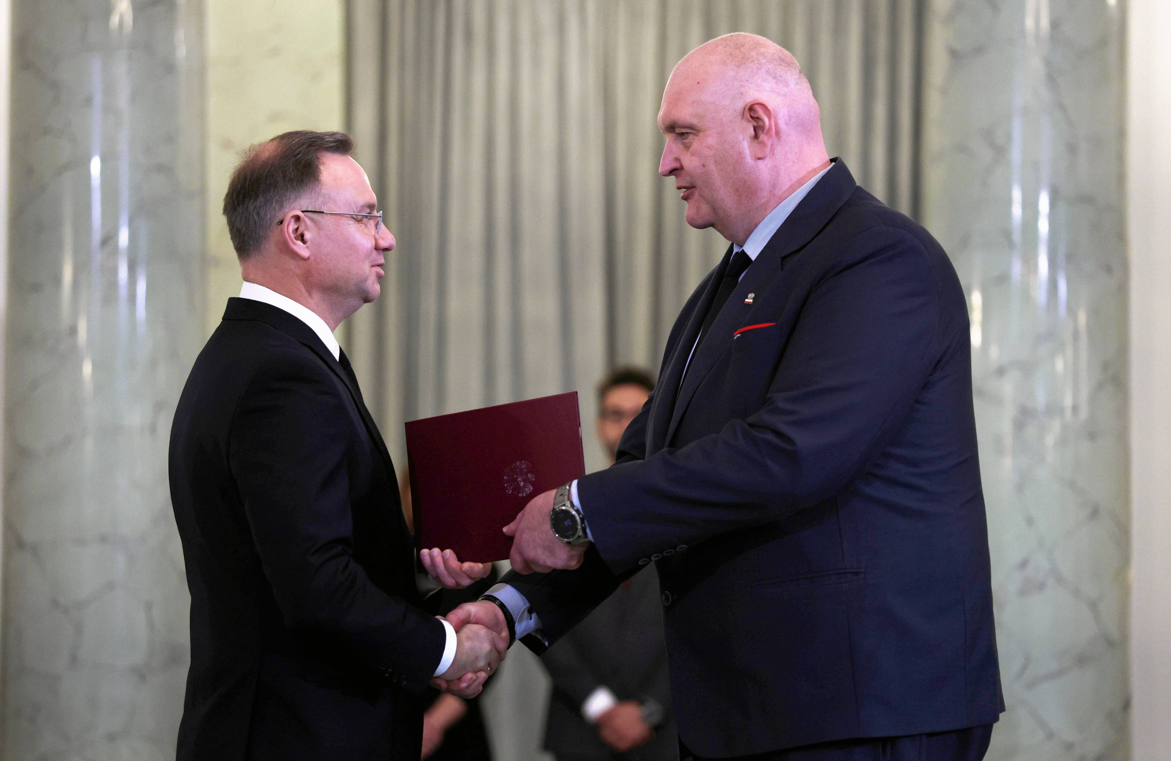 Dwaj mezczyźni w garniturach ściskaja sobie ręce. Wielki i łysy do Bogdan Święczkowski, drugi - to prezydent Dida