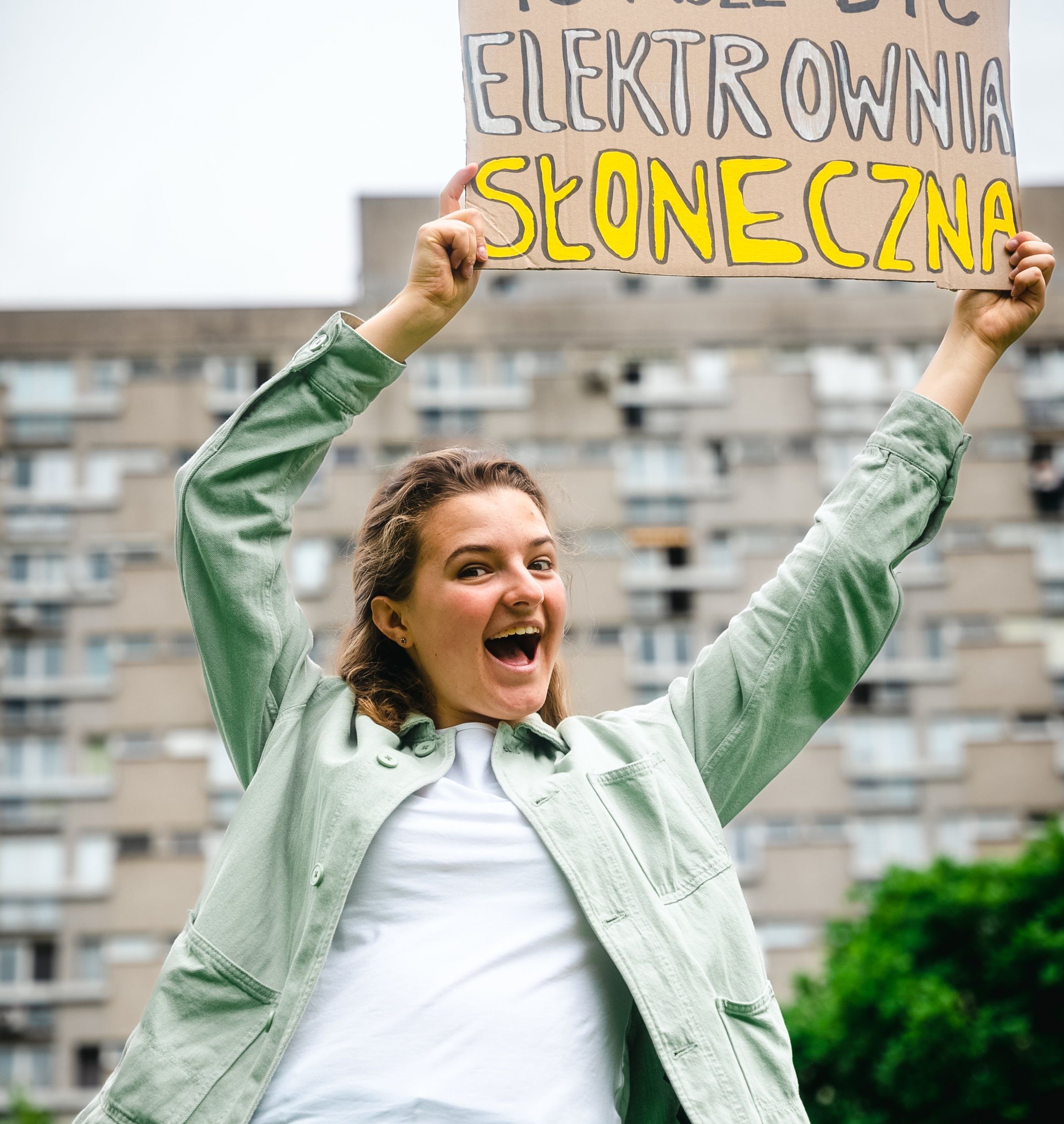 Młoda dziewczyna podnosi do góry transparent