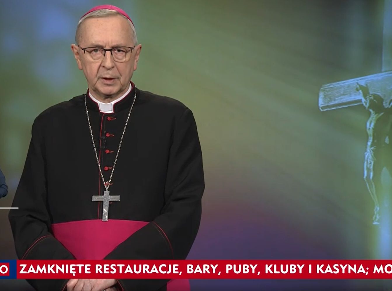 Abp Stanisław Gądecki na tle zielonej poświaty i krzyża.