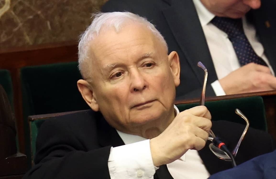 Jarosław Kaczyński w sejmowej ławie. Spogląda przed siebie z poważną miną, lekko unosząc brwi. W ręce trzyma okulary.