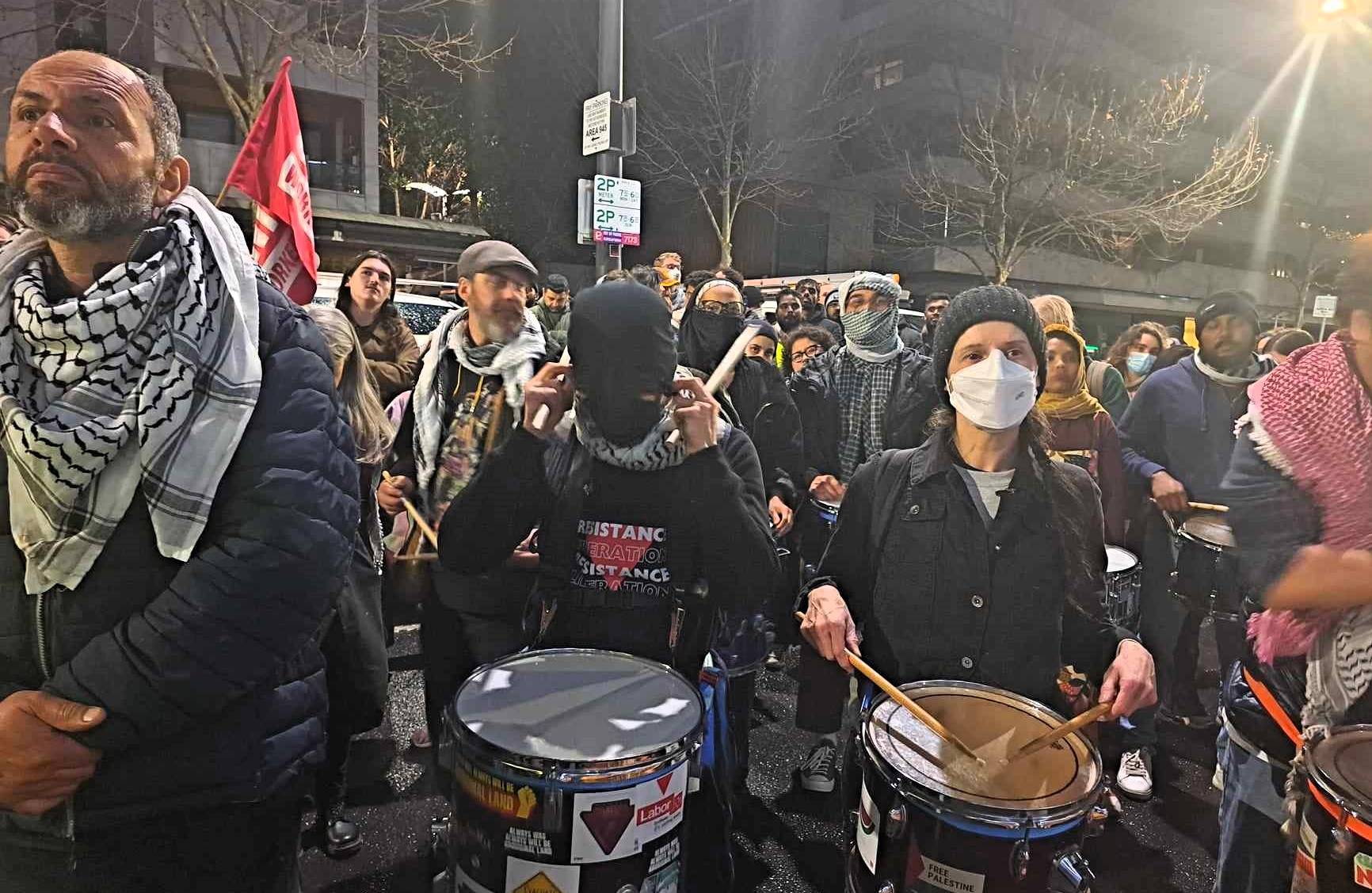 Zdjęcie z protestu ulicznego, młodzi ludzie grają na bębnach.