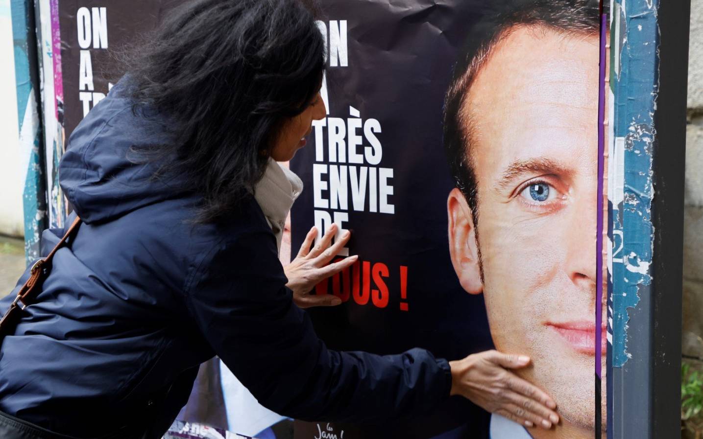 LREM and "Les Jeunes avec Macron" (JAM) supporters stick posters asking for the French president Emmanuel Macron's candidacy to the French presidential election, in Issy-les-Moulineaux, near Paris, on February 18, 2022, ahead of the April 2022 French presidential election. (Photo by Ludovic MARIN / AFP)
