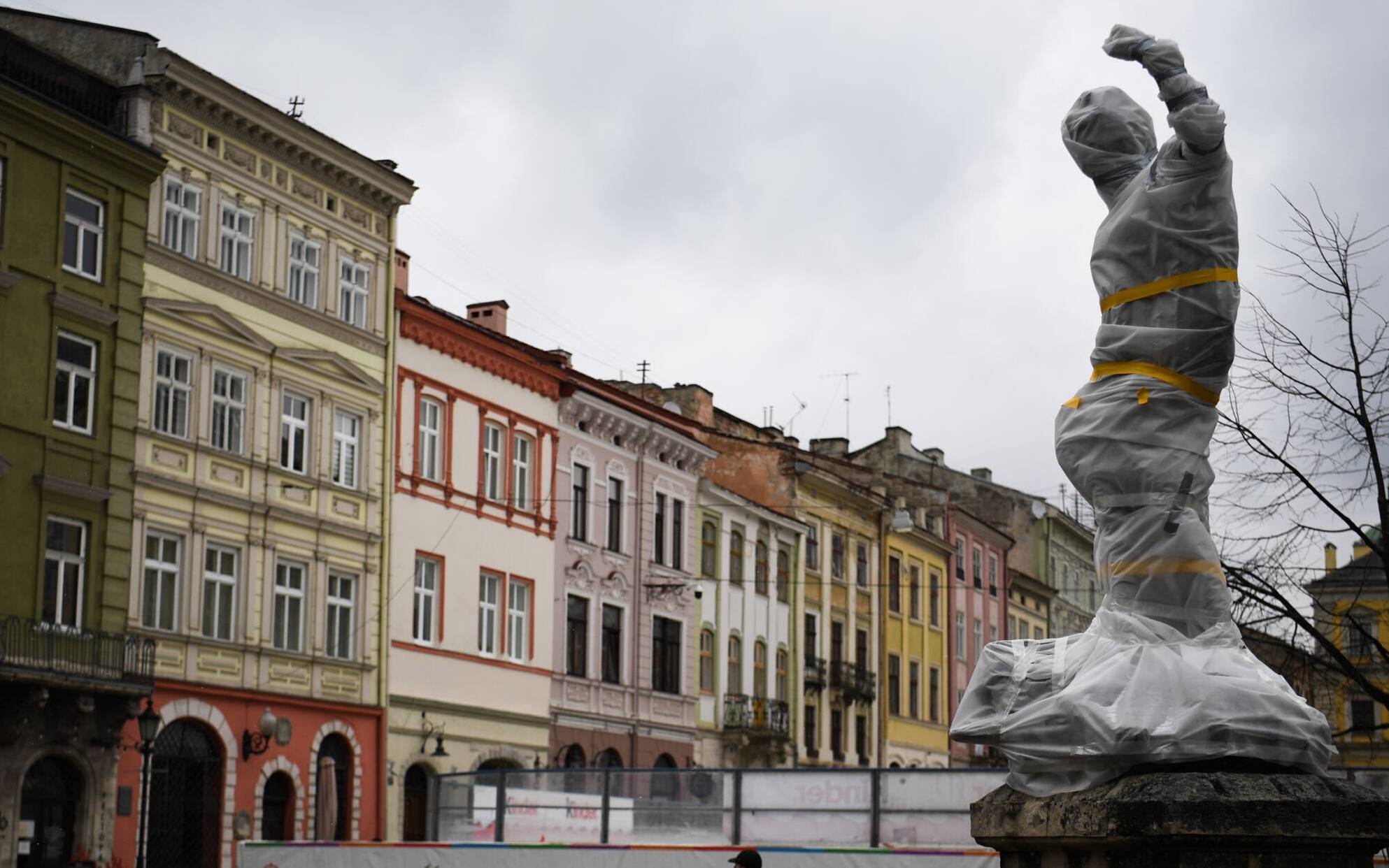 Pedestrians walk past a wrapped statue near the city council in Lviv western Ukraine, on March 5, 2022. (Photo by Daniel LEAL / AFP)