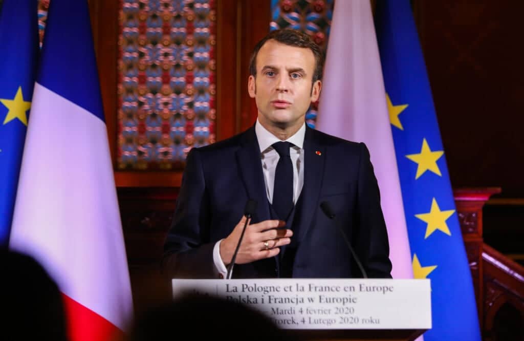 Emmanuel Macron przemawia na tle flag Francji i UE