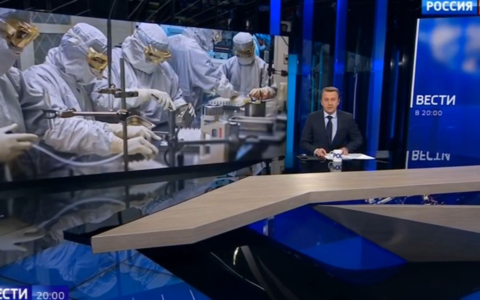 Studio telewizyjne, prowadzący, wtle zdjecie naukowców w ochronnych strojach w laboratorium