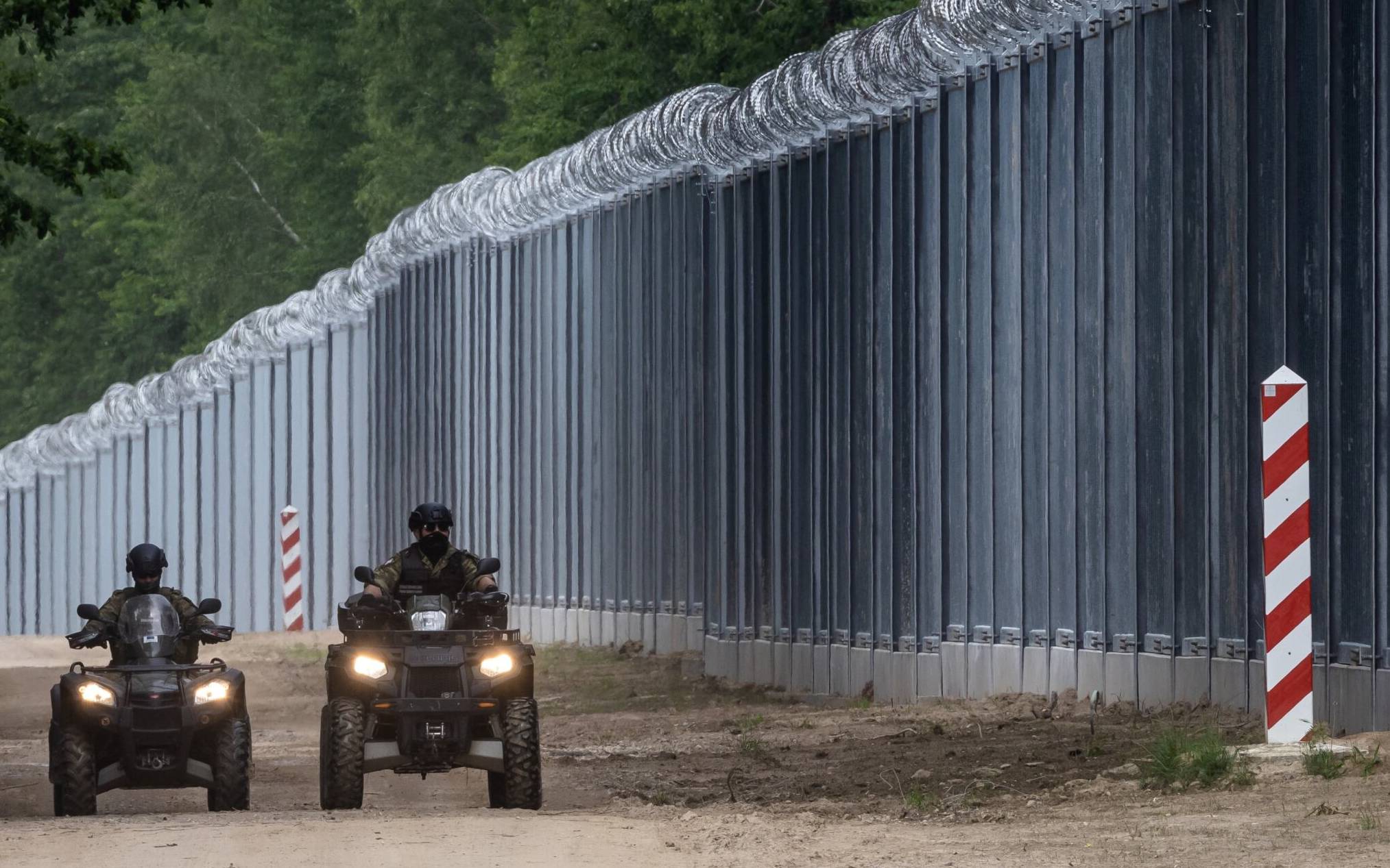 (FILES) In this file photo taken on June 08, 2022 border guards patrol on quads along the border wall at the Polish-Belarusian border near Tolcze village, in Sokolka County, Podlaskie Voivodeship, in north-eastern Poland. - Poland said on June 30, 2022 it had finished building a steel wall along the Belarus border to deter migrants, after it blamed Minsk for allowing in an influx to "destabilise" the region. Tens of thousands of migrants and refugees, mostly from the Middle East, have crossed or attempted to cross into Poland from Belarus since last summer. (Photo by Wojtek RADWANSKI / AFP)