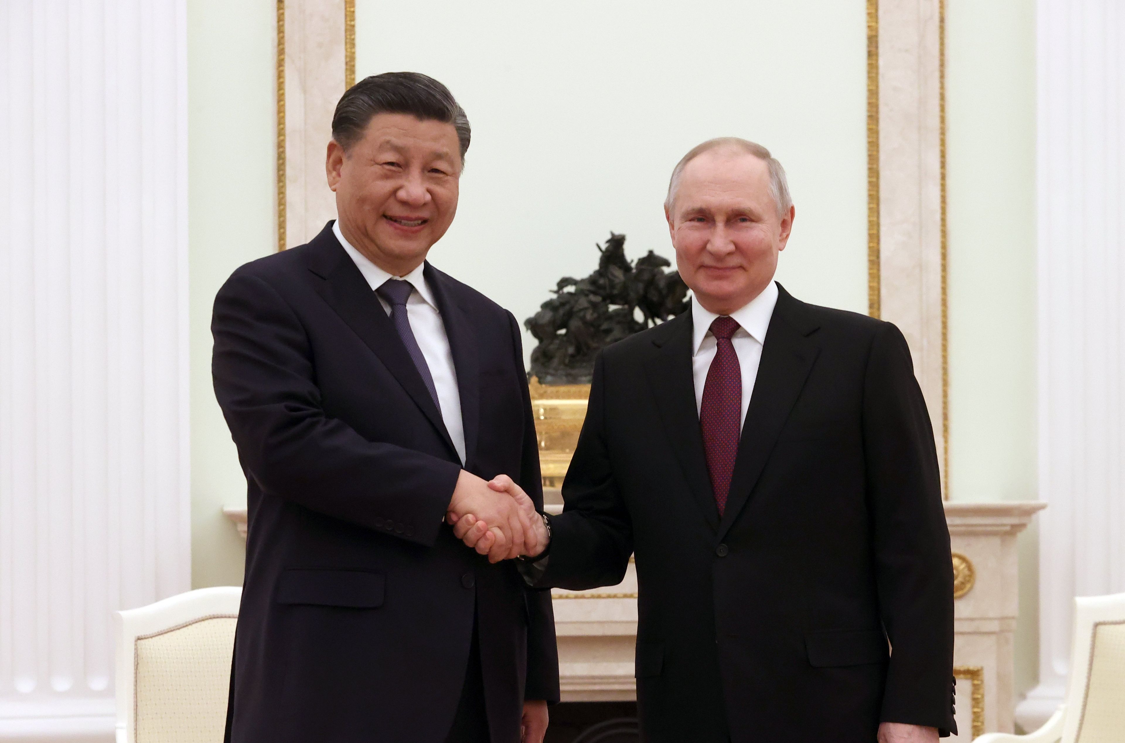 Dwaj mężczyźni w garniturach pozują ściskają dłonie. To Xi Jinping i Władimir Putin