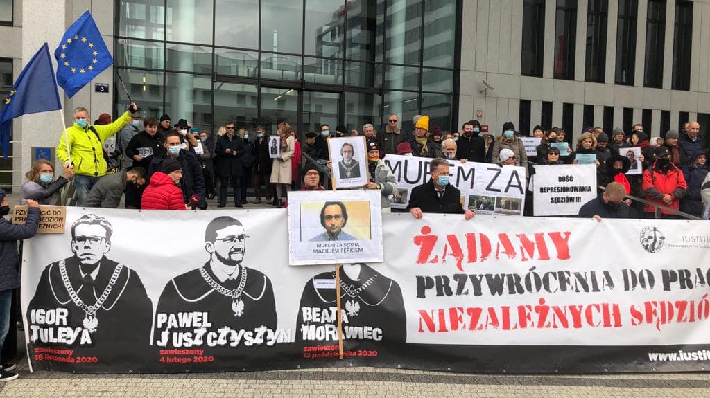 Krakowscy sędziowie stoją przed sądem z transparentami