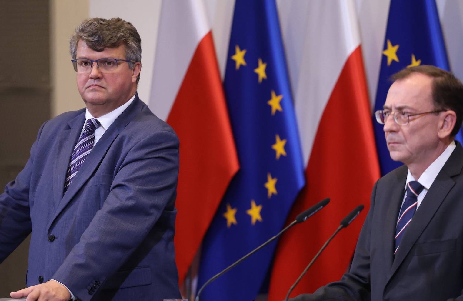 Maciej Wąsik i Mariusz Kamiński przemawiają z mównic na tle flag Polski i Unii Europejskiej