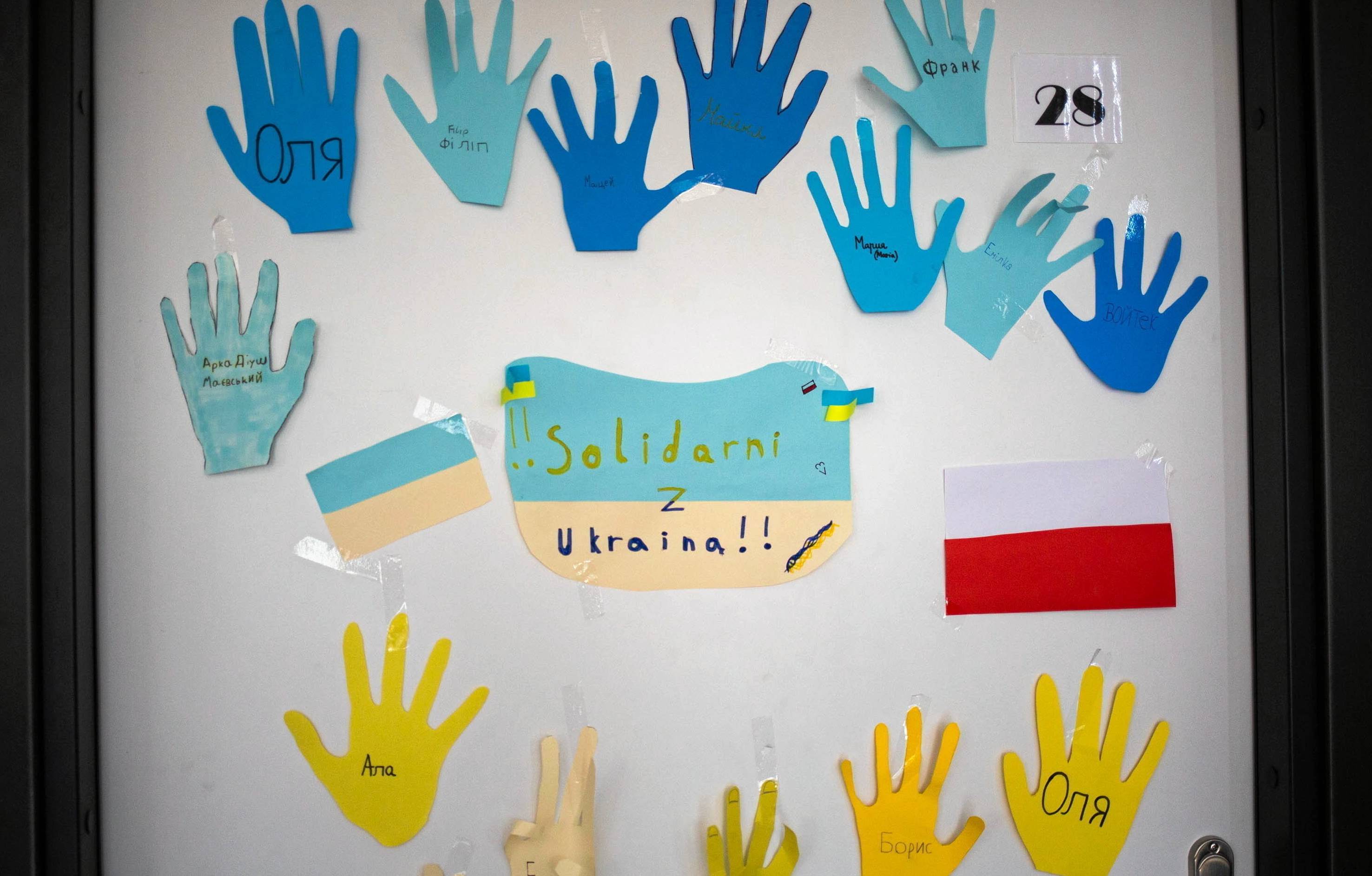 Szkolna wyklejanka: niebieskie i żółte dłonie, w które spiane są imiona ukraińskich dzieci. Flaga Polski i Ukrainy, napis "Solidarni z Ukrainą"