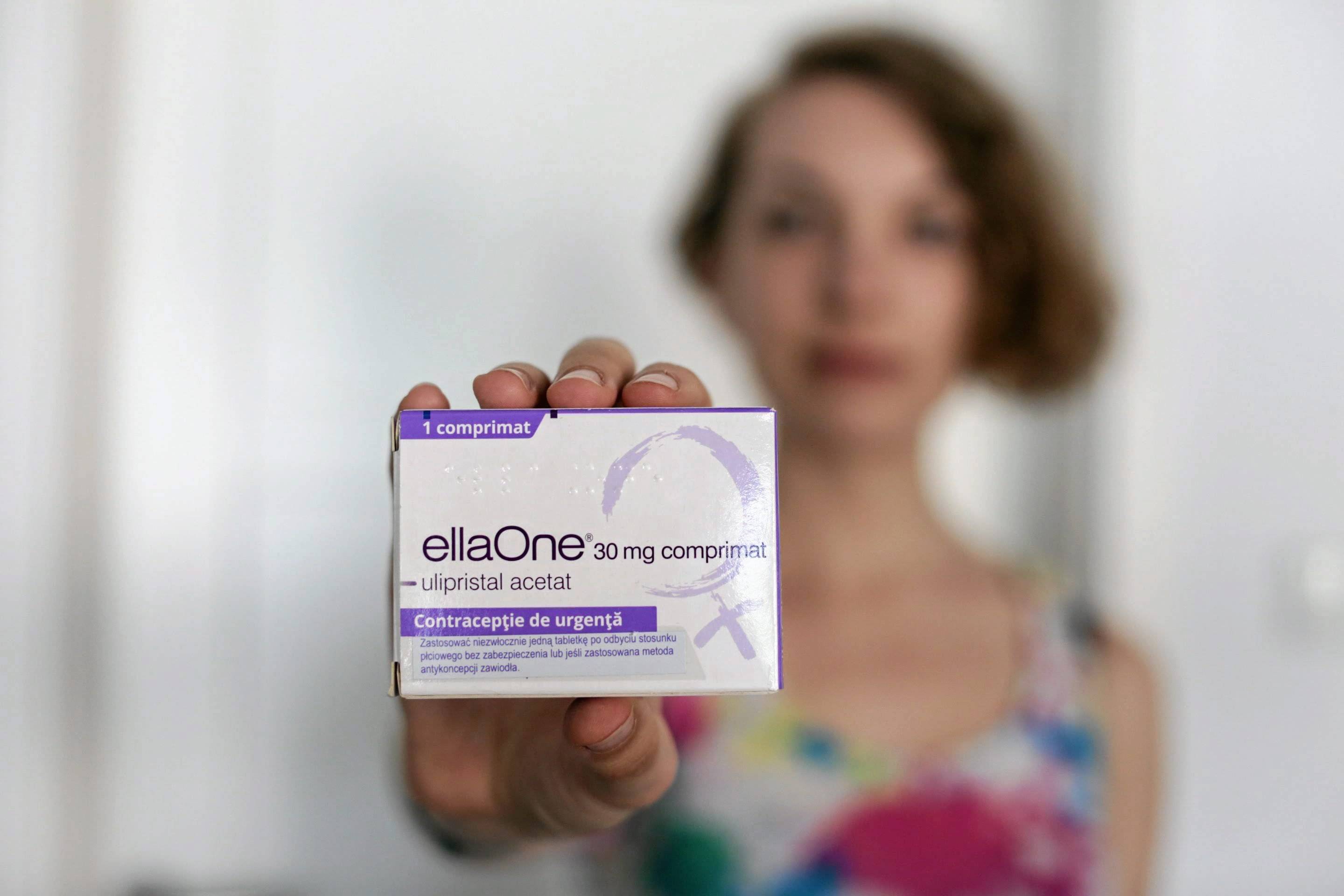 Kobieta trzyma przed sobą opakowanie tabletki EllaOne