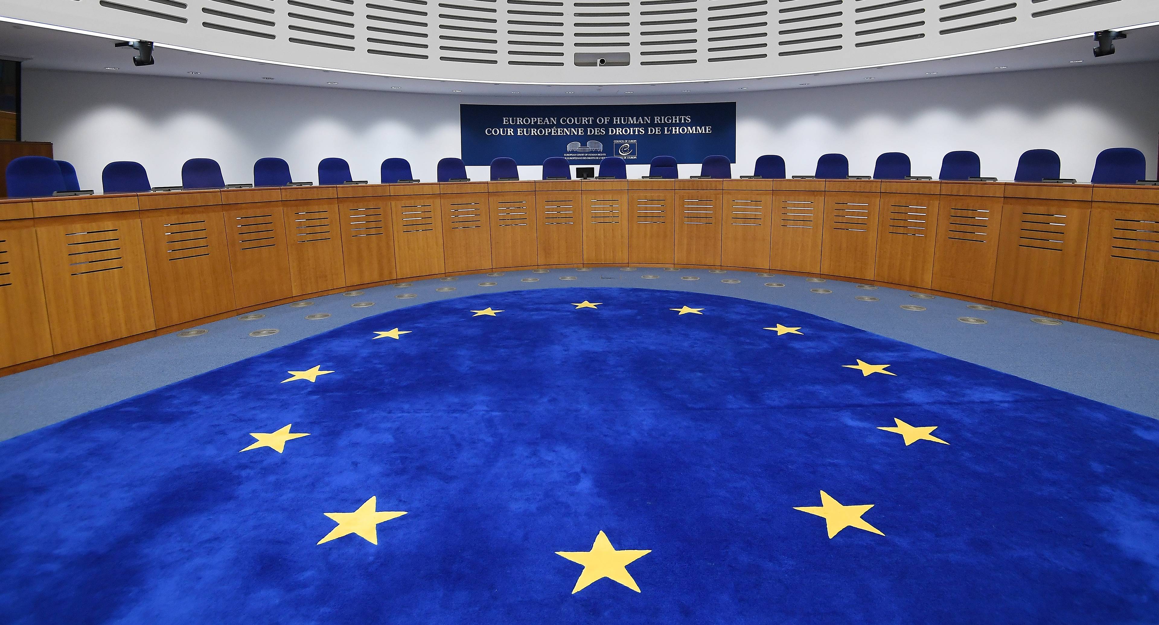 Sala trybunału z niebieskim dywanem w unijne gwiazdy. Siedziba Europejskiego Trybunału Praw Człowieka (ETPCz)