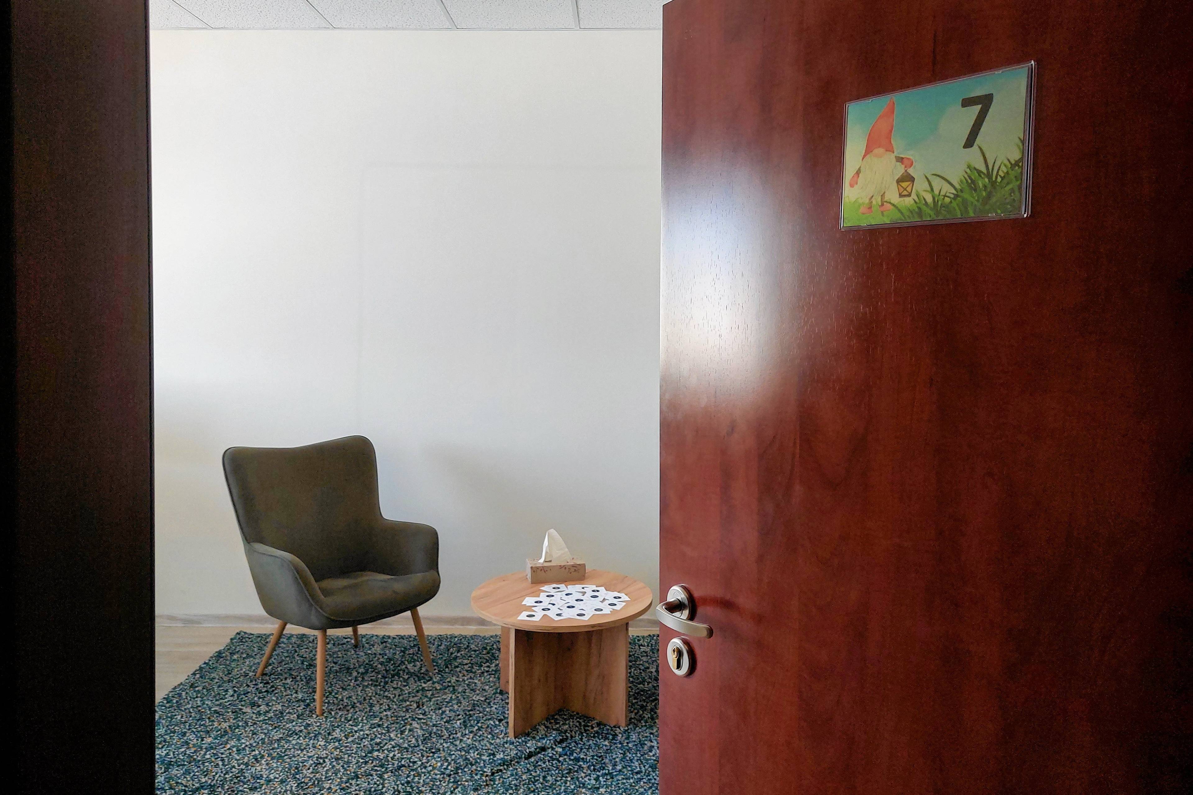 Otwarte drzwi do gabinetu psychologa: widać fotel i stolik