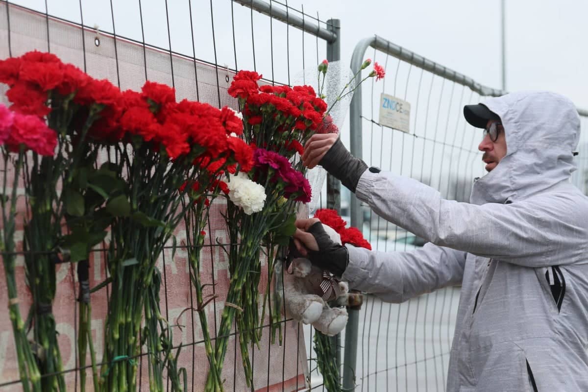 A man places flowers at a makeshift memorial in front of the Crocus City Hall, A day after a gun attack in Krasnogorsk, outside Moscow, on March 23, 2024. - Gunmen who opened fire at a Moscow concert hall killed more than 60 people and wounded over 100 while sparking an inferno, authorities said on March 23, 2024, with the Islamic State group claiming responsibility. (Photo by STRINGER / AFP)