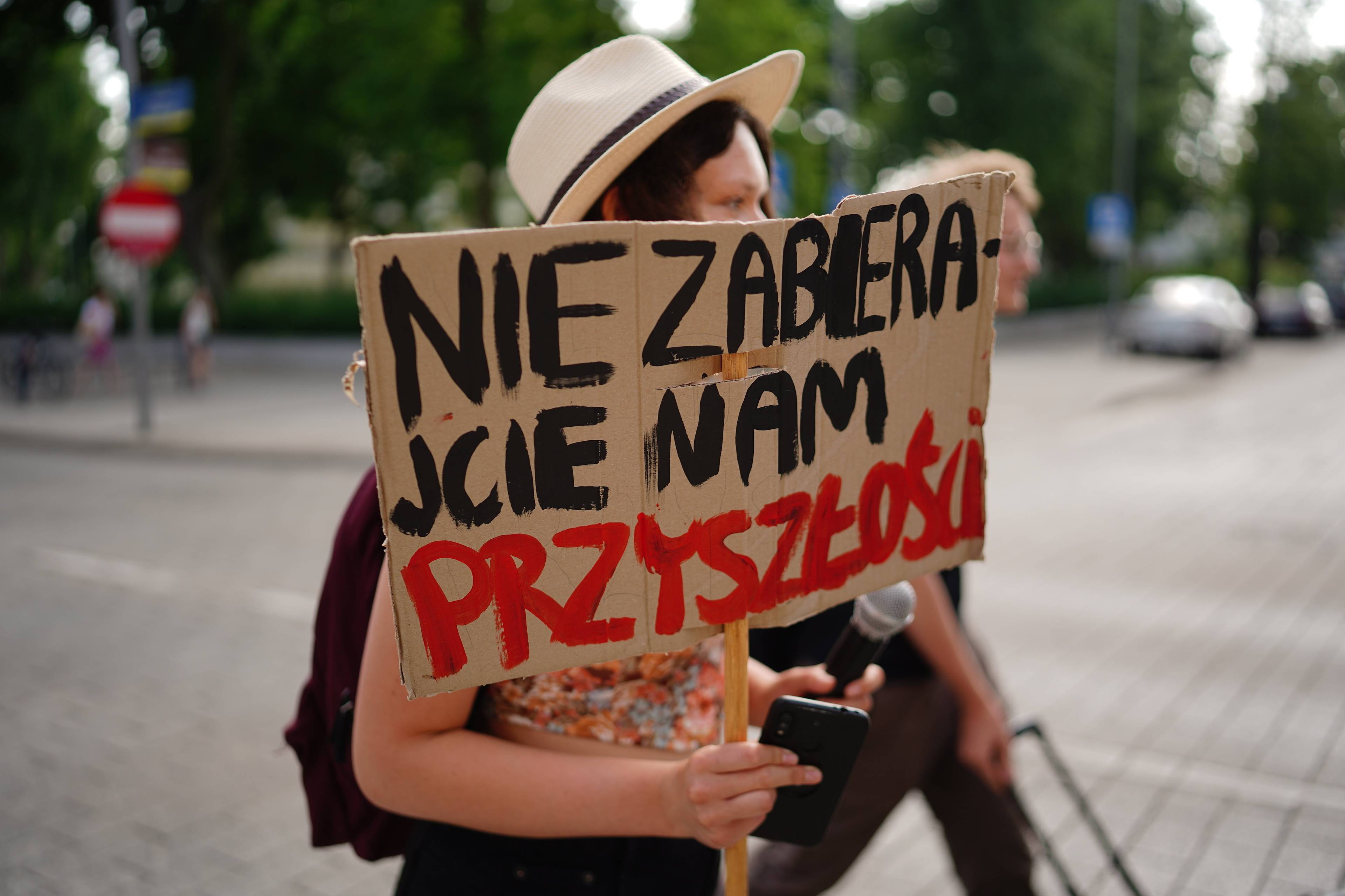 Młoda kobieta z plakatem, na którym napisała "Nie zabierajcie nam przyszłości"