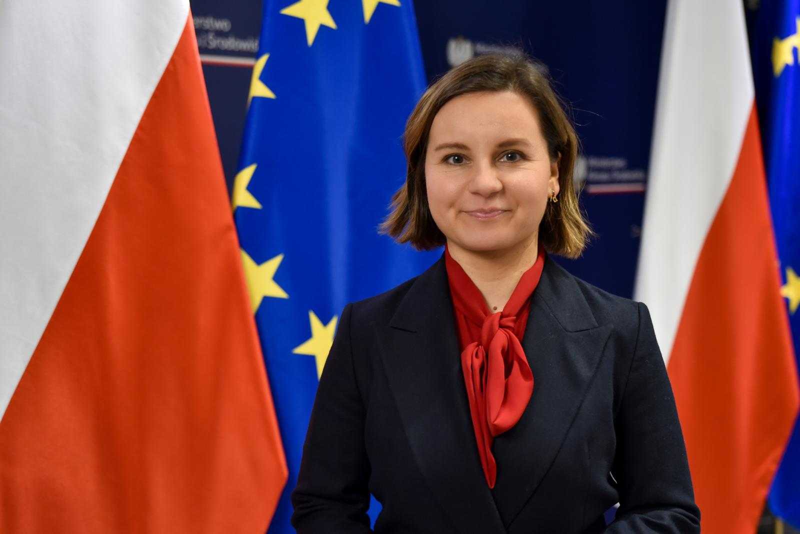 Kobieta stoi na tle flag Polski i UE