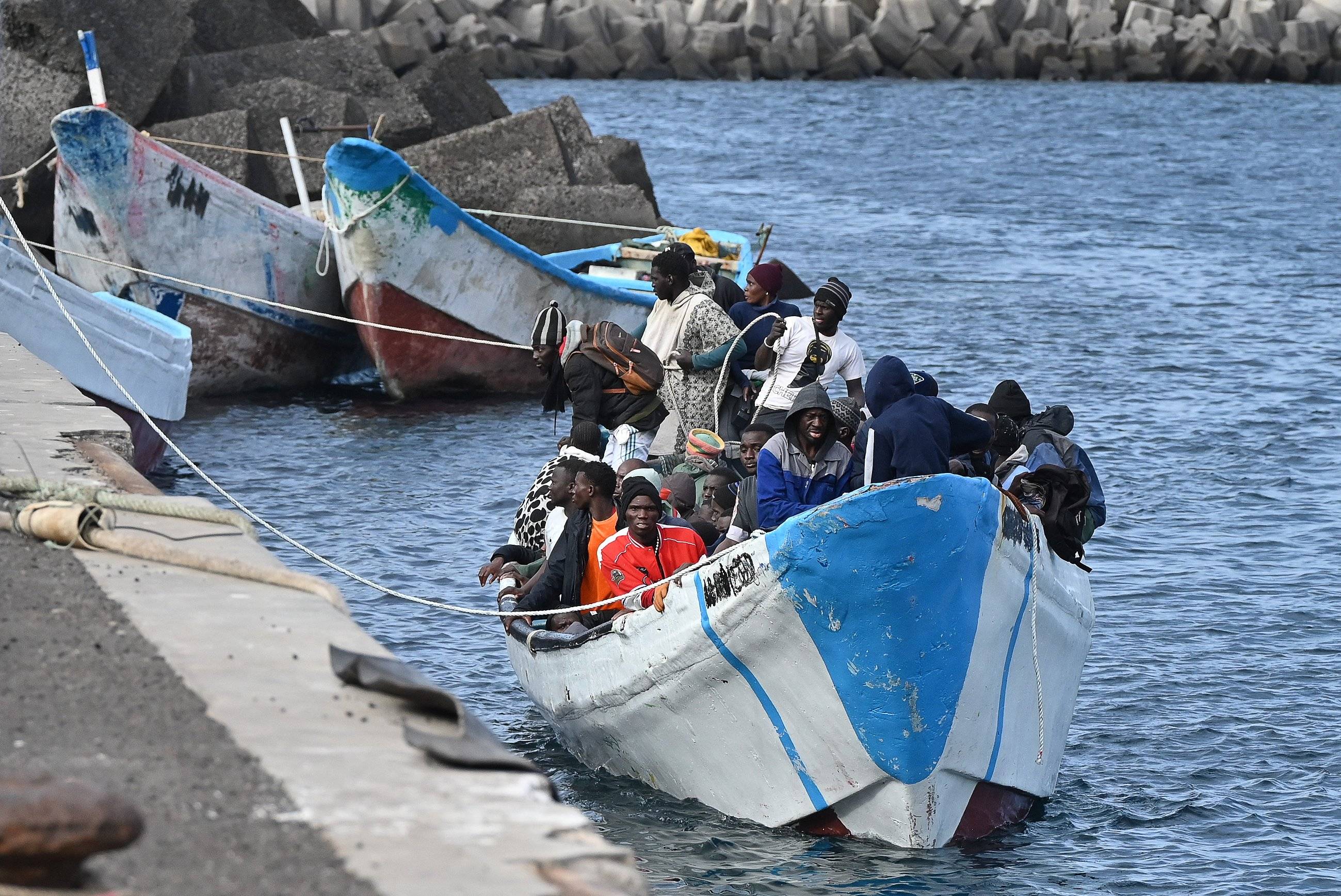 Dobijająca do brzegu łódź pełna migrantów z Afryki. Pakt migracyjny