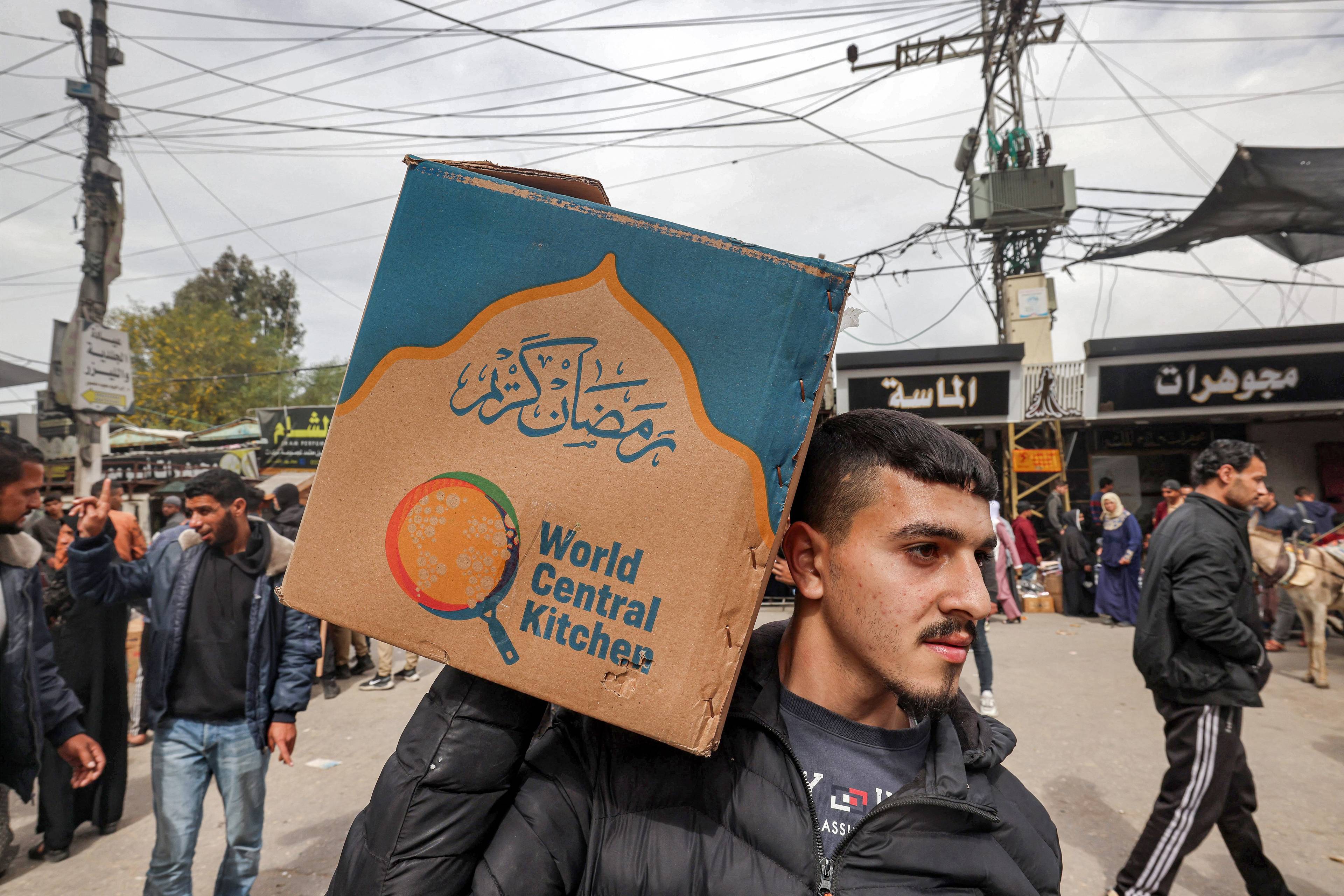 Palestyński mężczyzna trzyma na ramieniu pudło z napisem "World Central Kitchen"