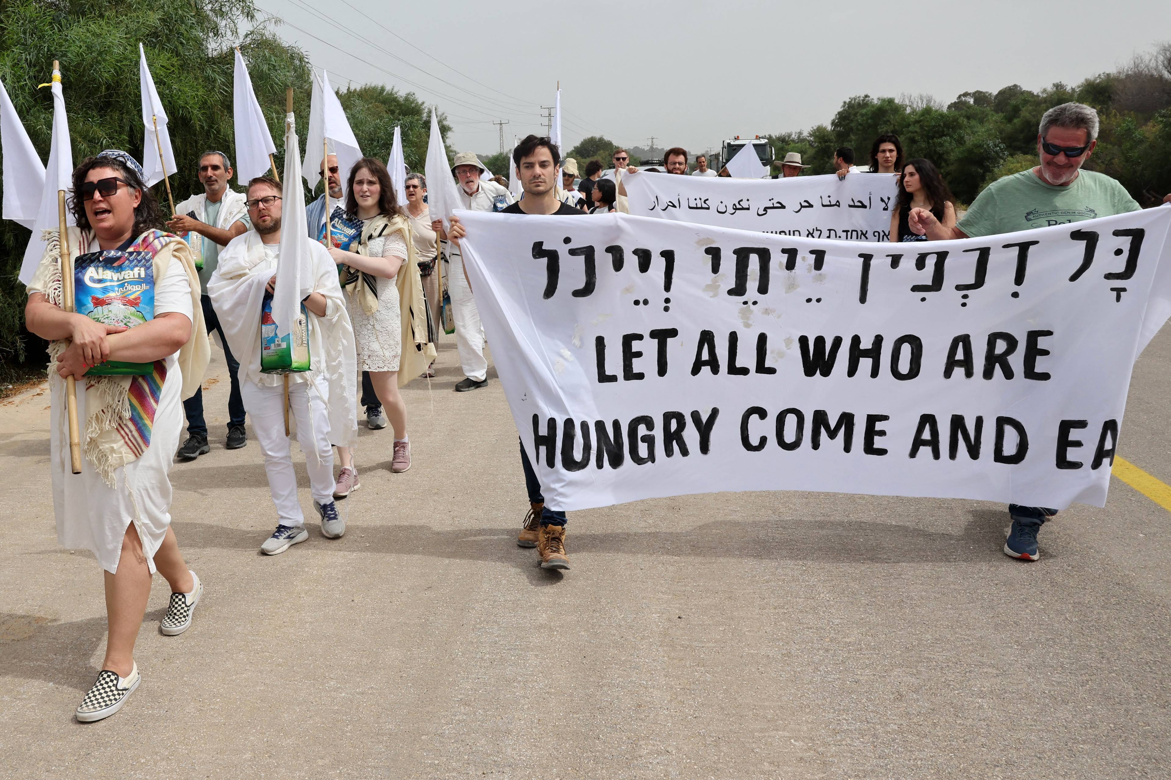 ubrani na biało protestujący niosą napis "let all who are hungry come and eat"