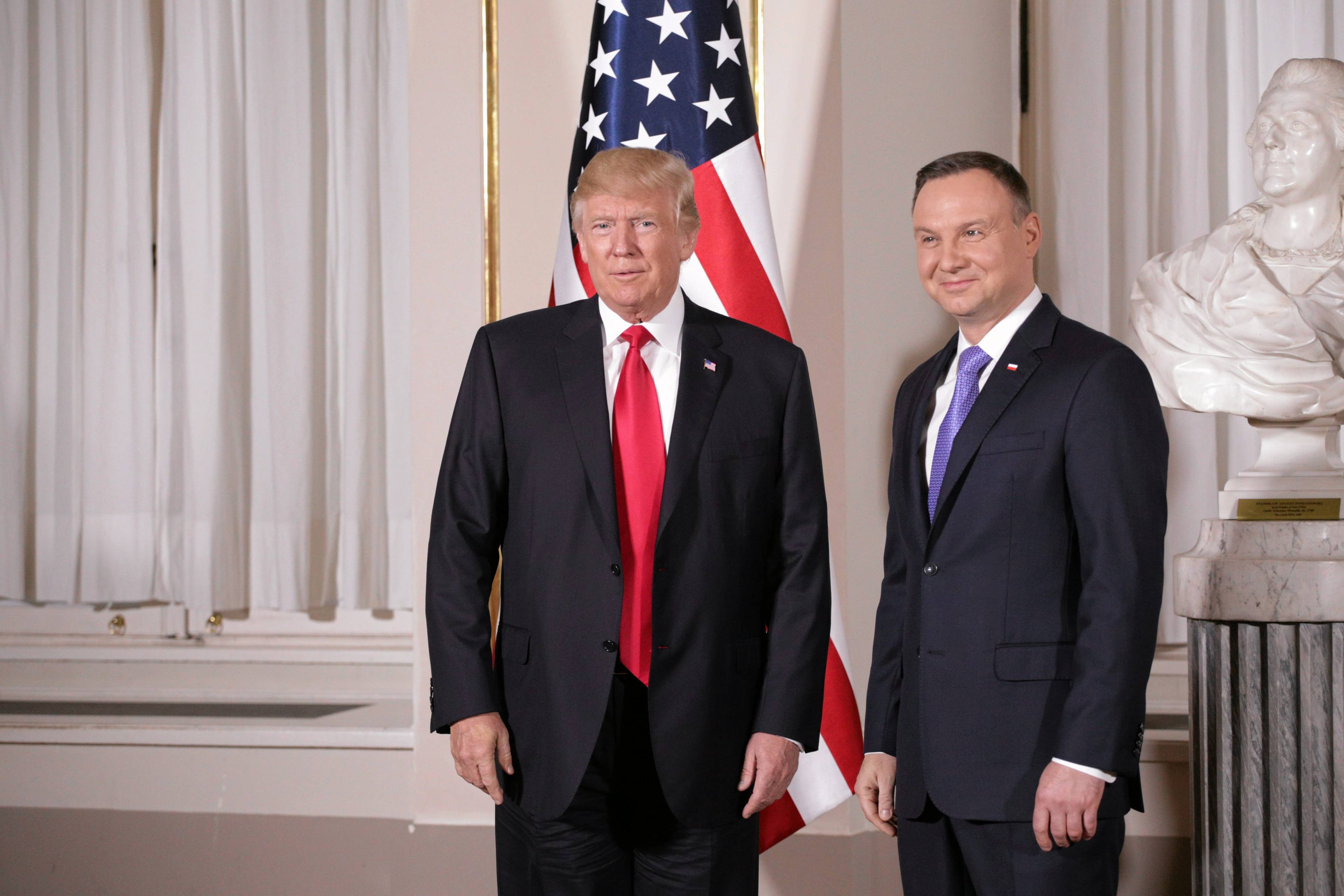 Andrzej Duda i Donald Trump stoją obok siebie, w tle amerykańska flaga