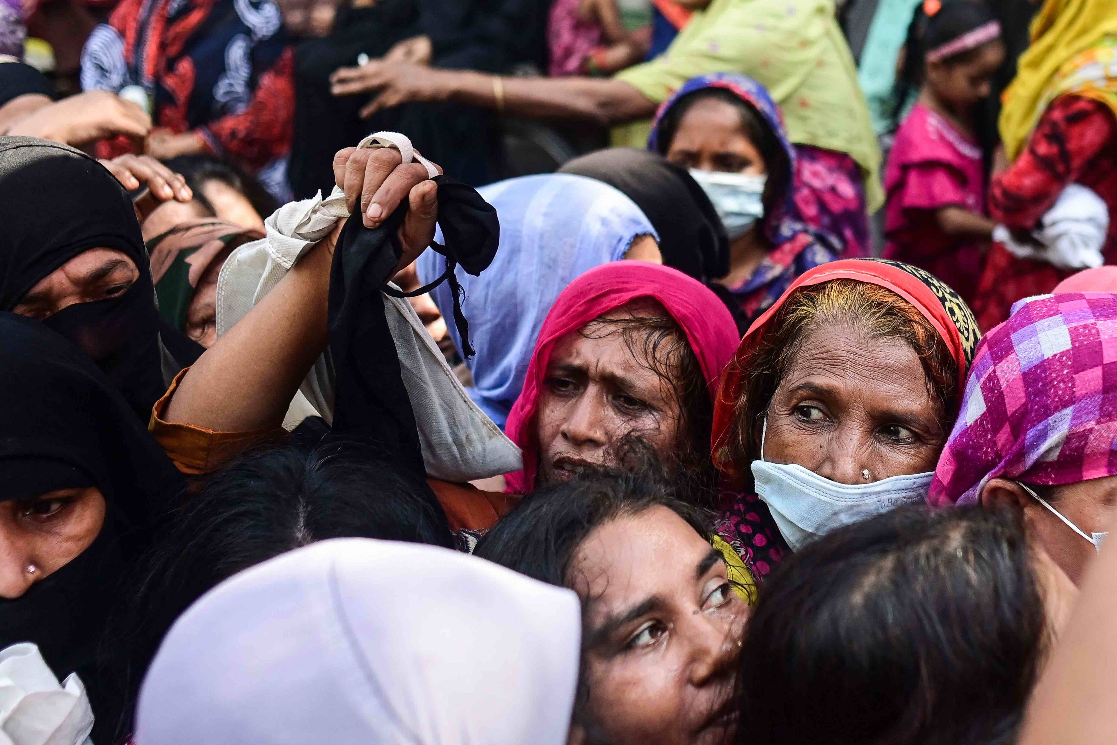 Kobiety w kolorowych chustachj na głowach tłoczą się w kolejce po żywność. Bangladesz
