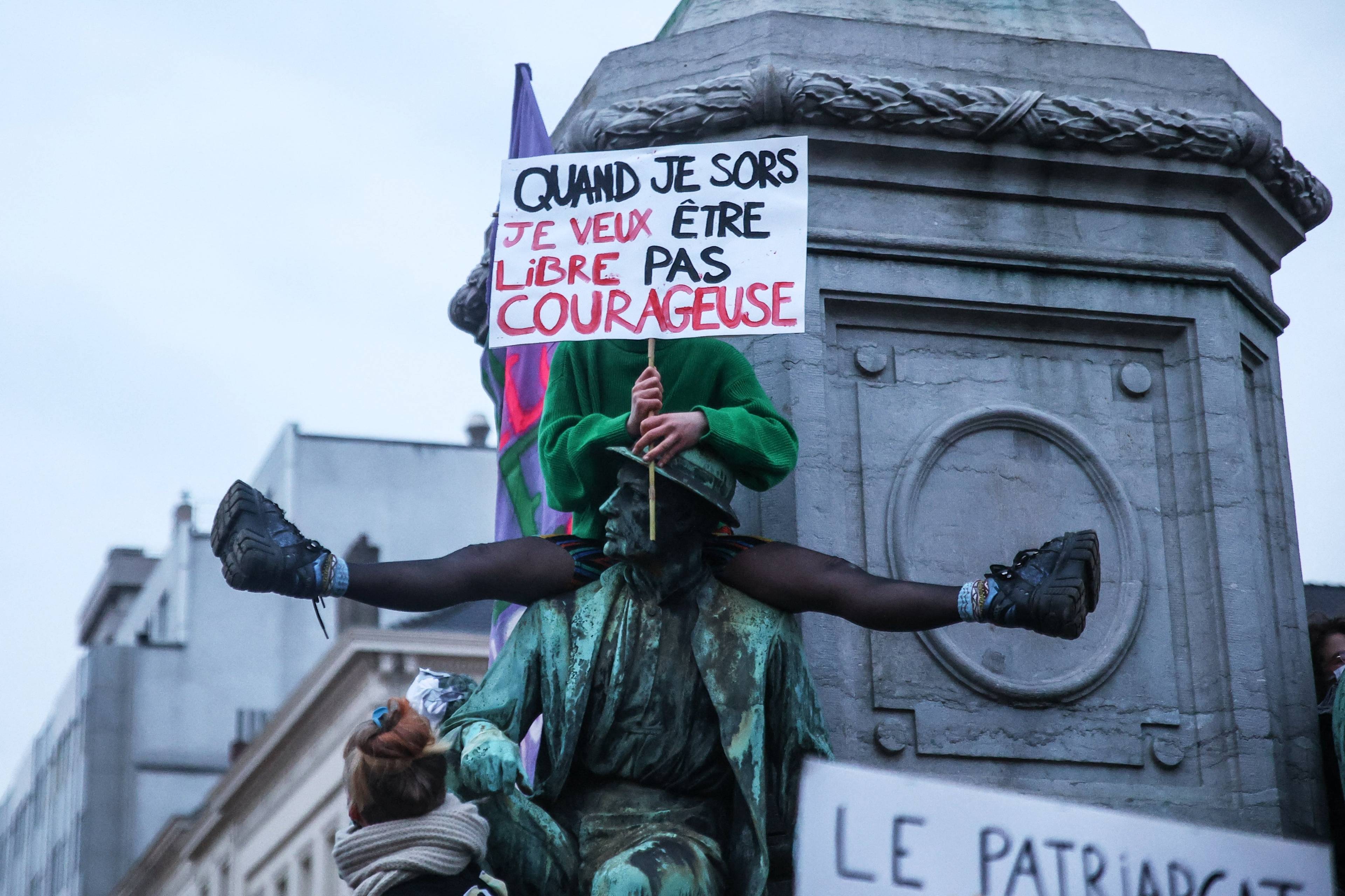 Aktywistka trzyma transparent po francusku "Kiedy wychodzę z domu, chcę być wolna a nie odważna"